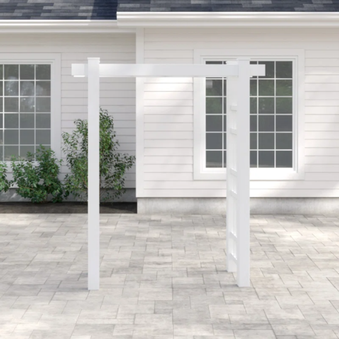 A white wooden garden arbor in front of a house with large windows and white siding available for rent for your special day..