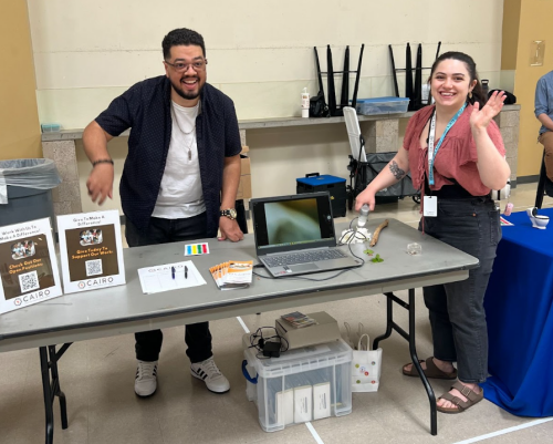 two people waving from behind a table