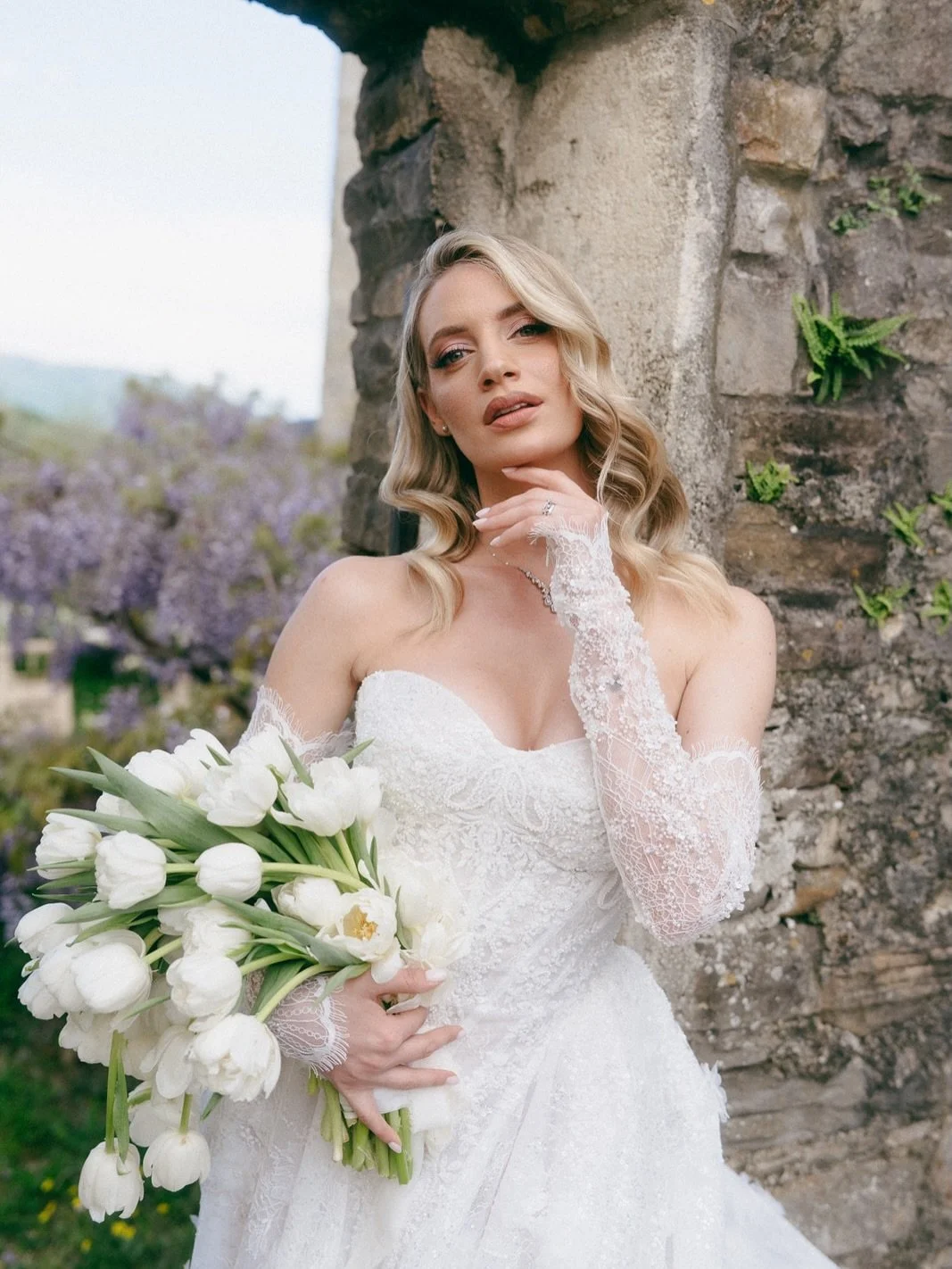 The Bride: A vision in lace and light. 

There is a certain magic in the moments just before the &ldquo;I do.&rdquo;
Draped in delicate lace and a veil that catches the Istrian breeze, our bride carries a modern rainfall bouquet of white tulips&mdash