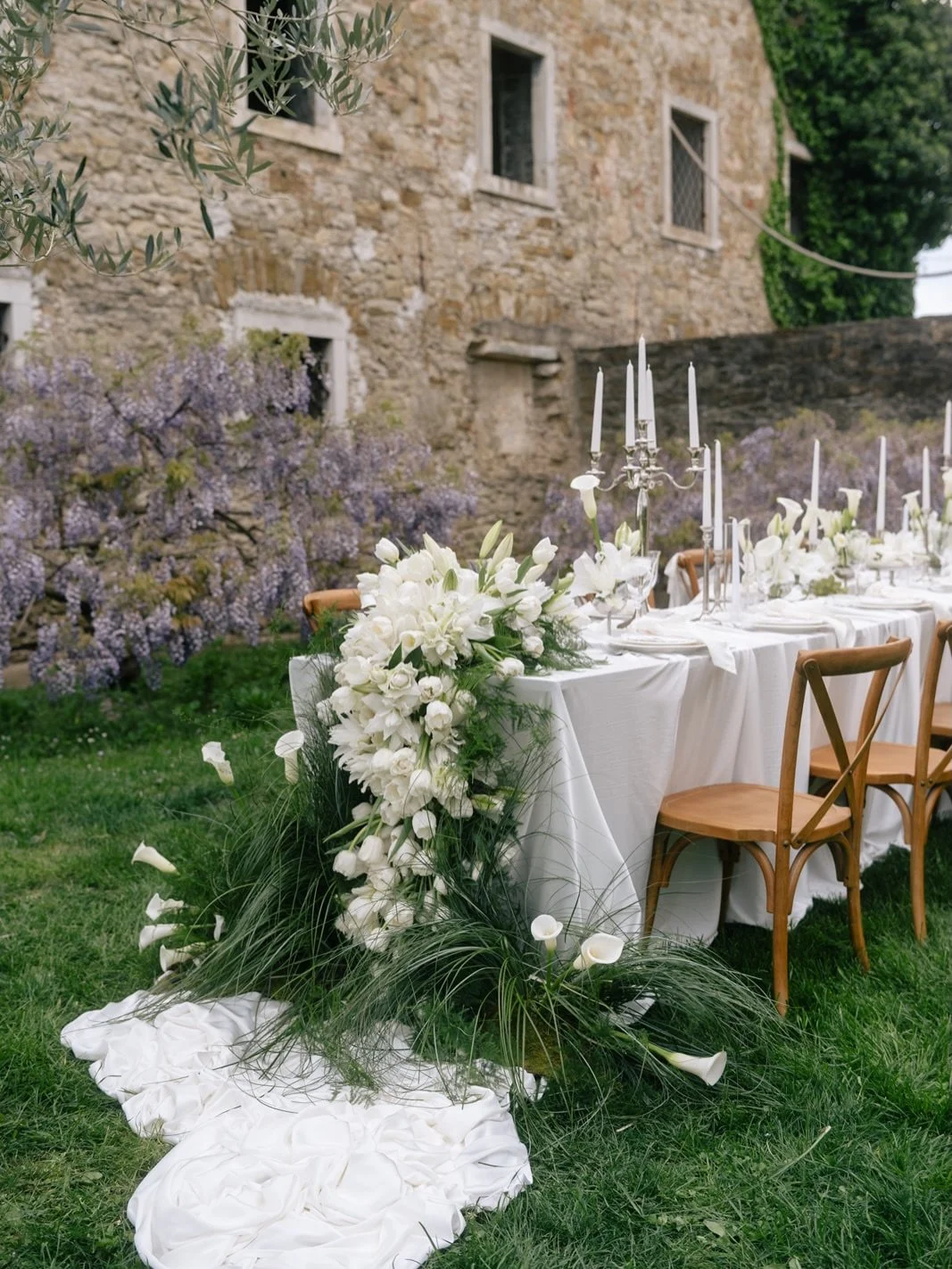 Continuing our ETHEREAL ELEGANCE photo series at @castlebelaj with the dinner setup.

Set in the green meadow surrounded by olive trees, the dinner table stands as a breathtaking
statement against the historical stone. A sculptural tulip rainfall flo