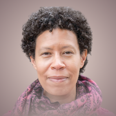 Close-up of a woman with short, curly hair wearing a purple scarf and a neutral background.