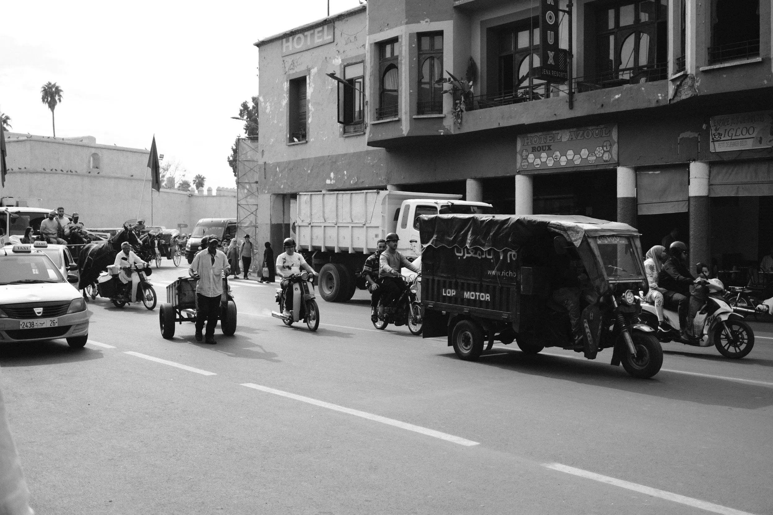 Black and white street scene with motorbikes and a delivery truck, Taghazout, Morocco - fine art print by Zyan Sachs