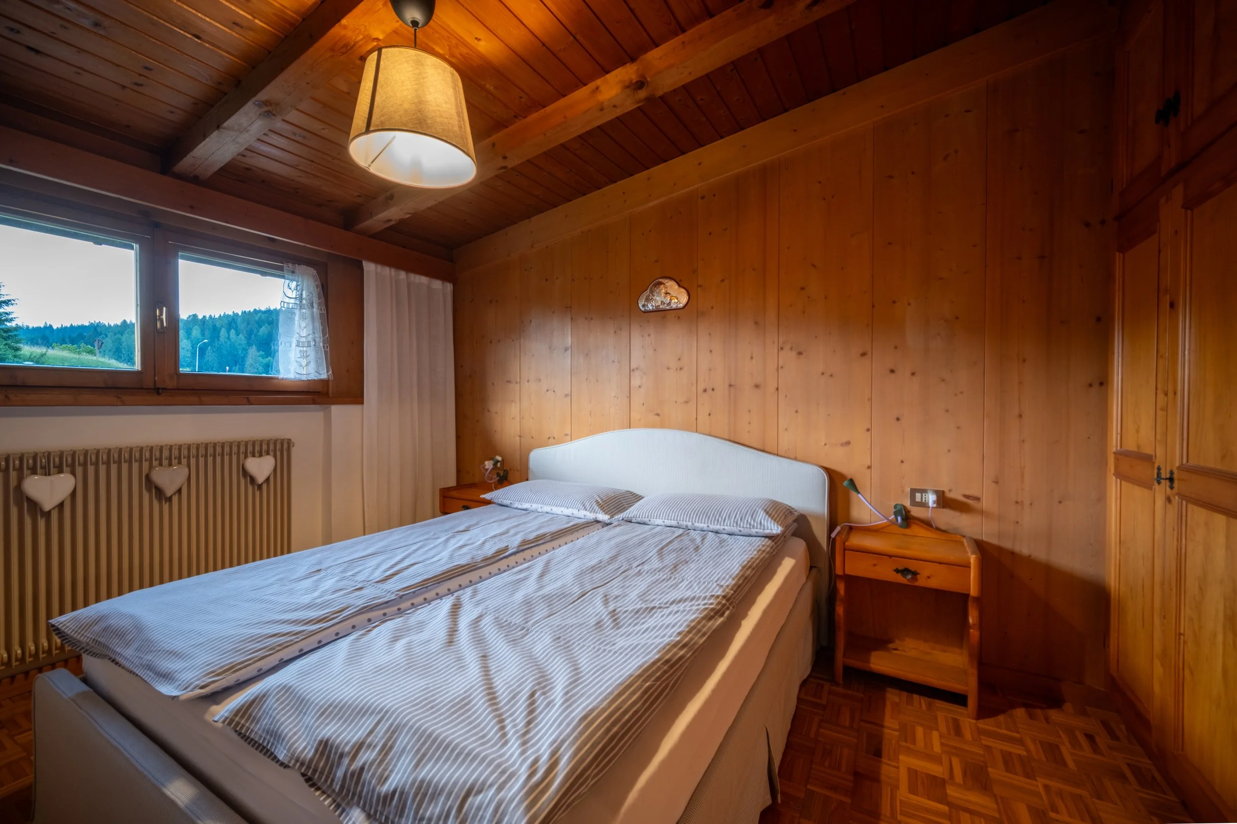 Bedroom with wooden walls and a window at Al Borgo da Agata, Dolomites, by Zyan Sachs