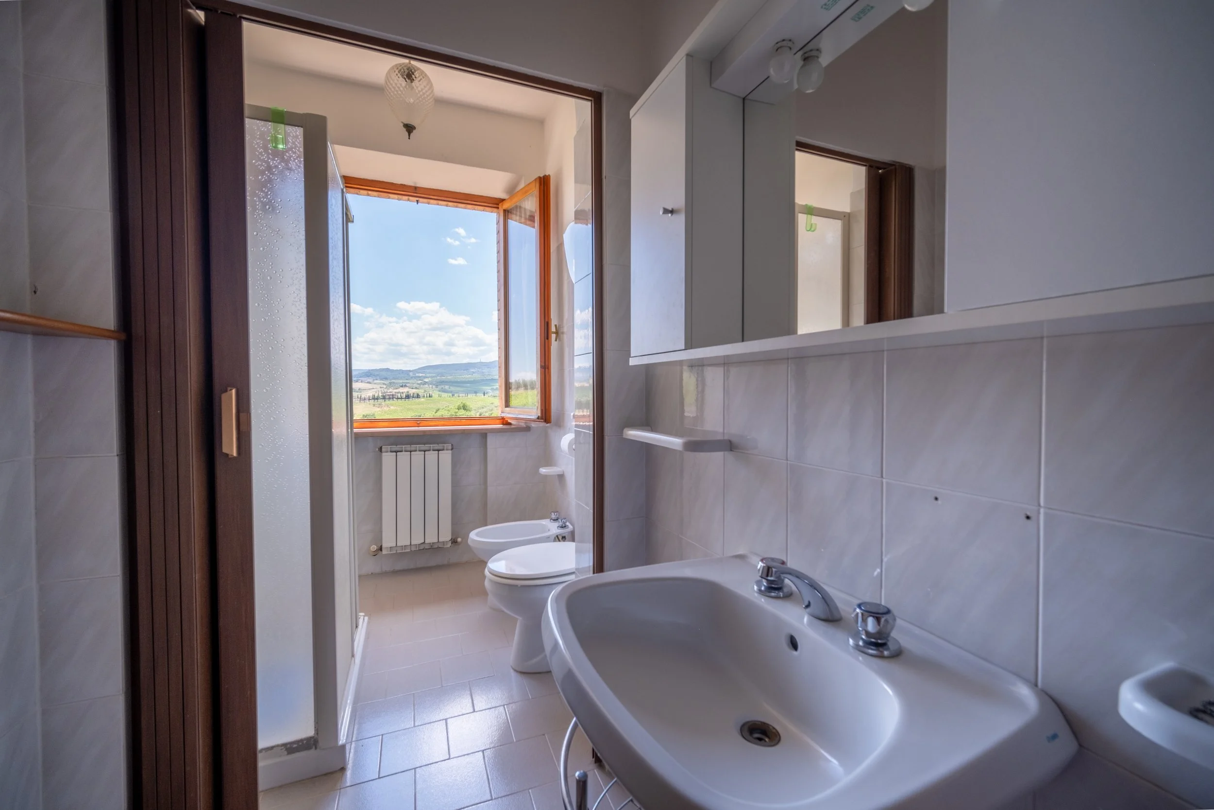 Bright apartment bathroom with a window onto the garden at Agriturismo Metina, Montepulciano, Tuscany, by Zyan Sachs
