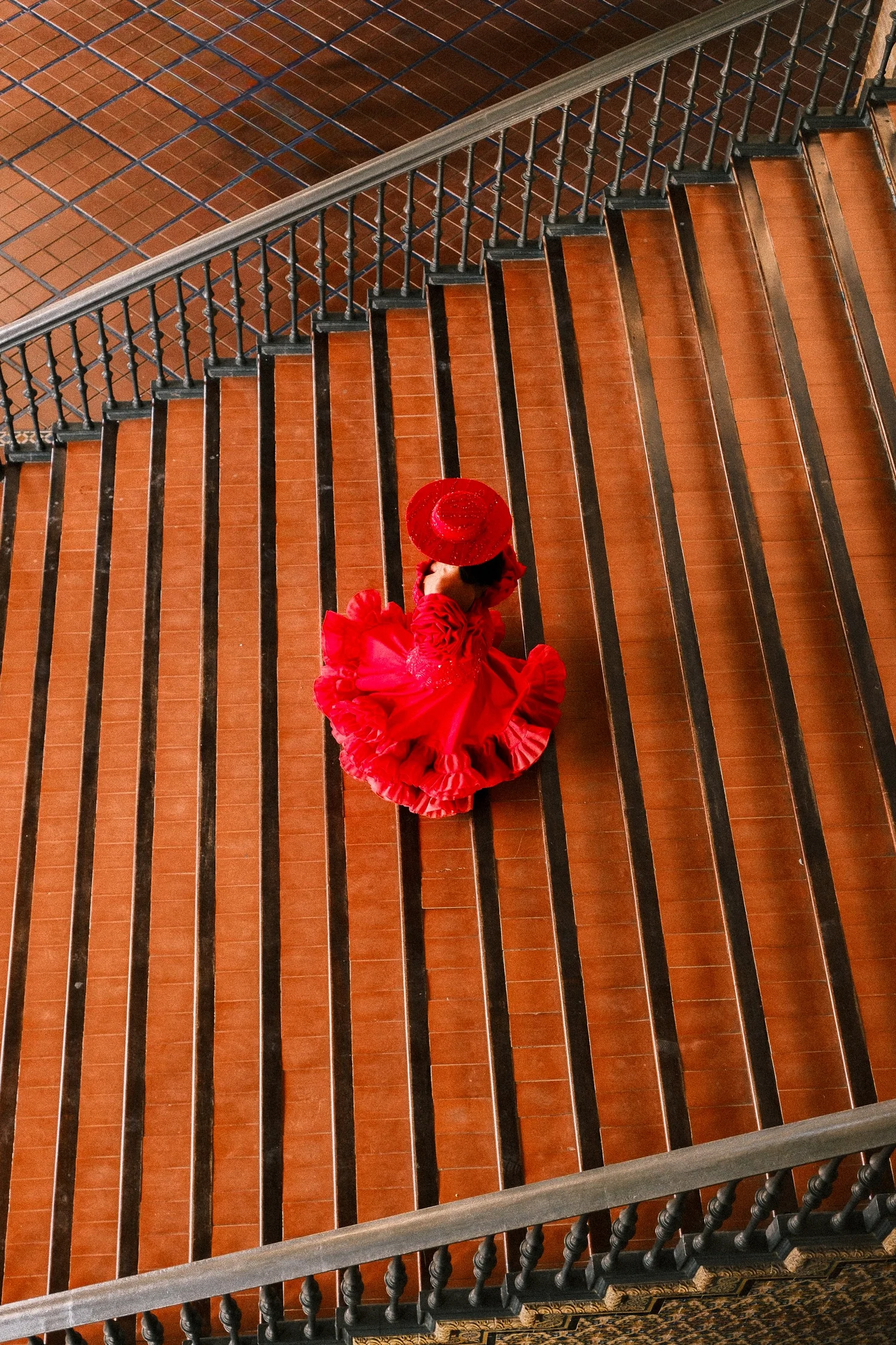 Flamenco dancer in a red dress seen from above on a tiled staircase, Sevilla, Spain - fine art print by Zyan Sachs