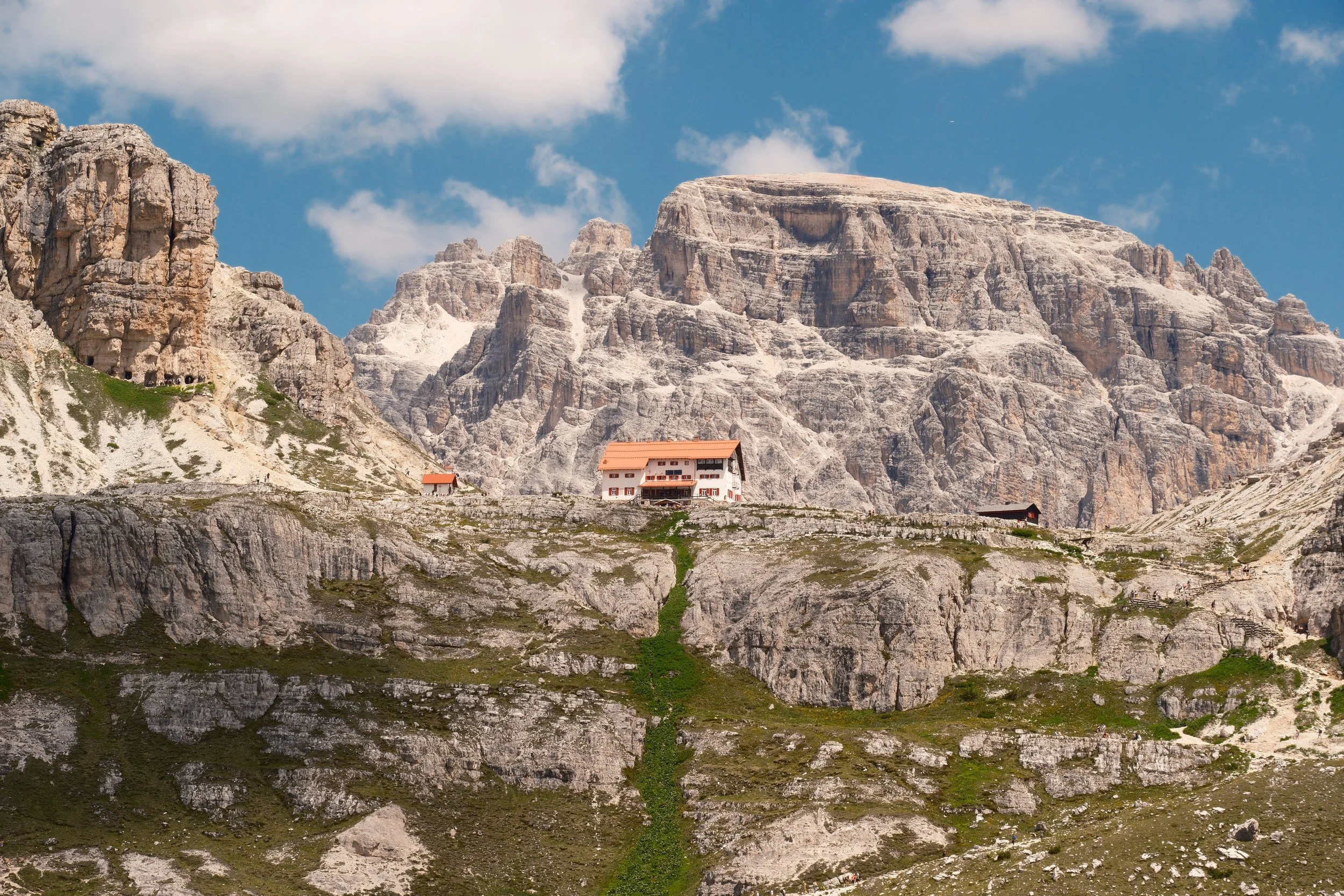 Orange-roofed Rifugio Locatelli perched below limestone peaks on the Tre Cime di Lavaredo trail, Dolomites, Italy, by Zyan Sachs