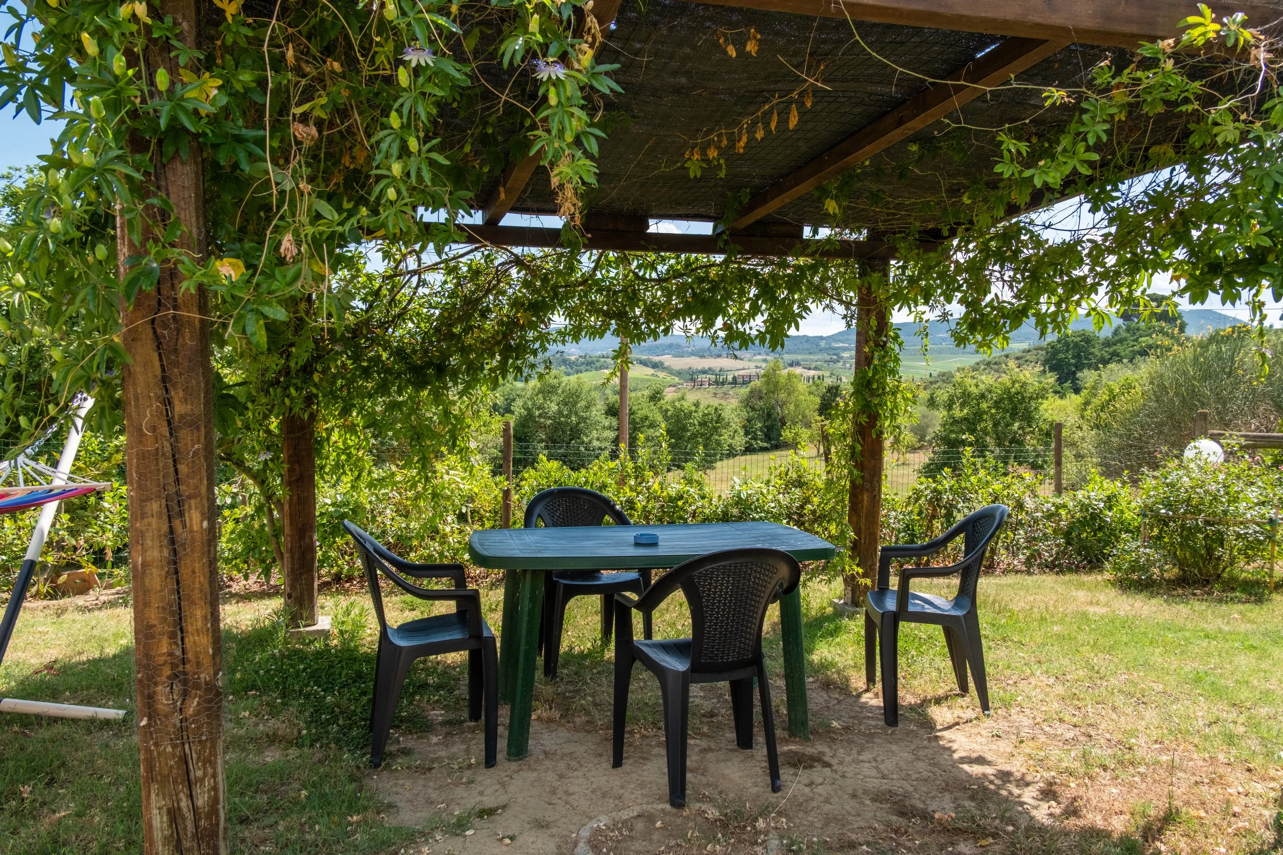 Shaded table under a vine-covered pergola at Agriturismo Metina, Montepulciano, Tuscany, by Zyan Sachs
