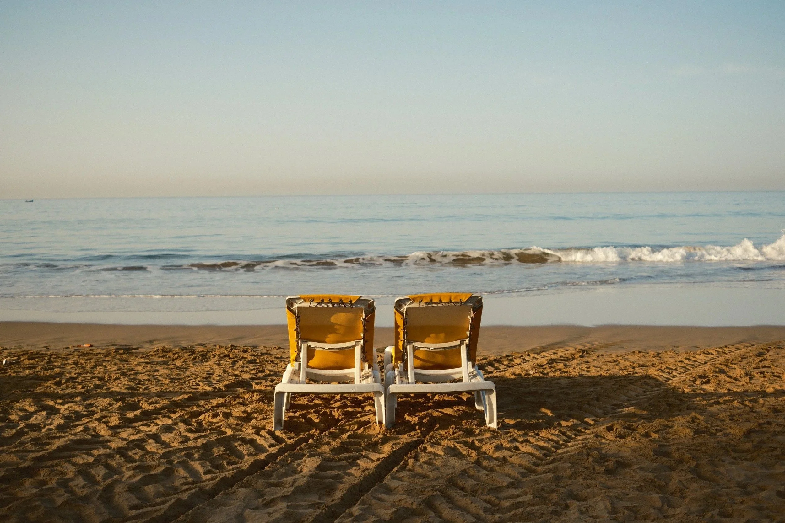 Two empty beach chairs facing the ocean on the sand, Taghazout, Morocco - fine art print by Zyan Sachs