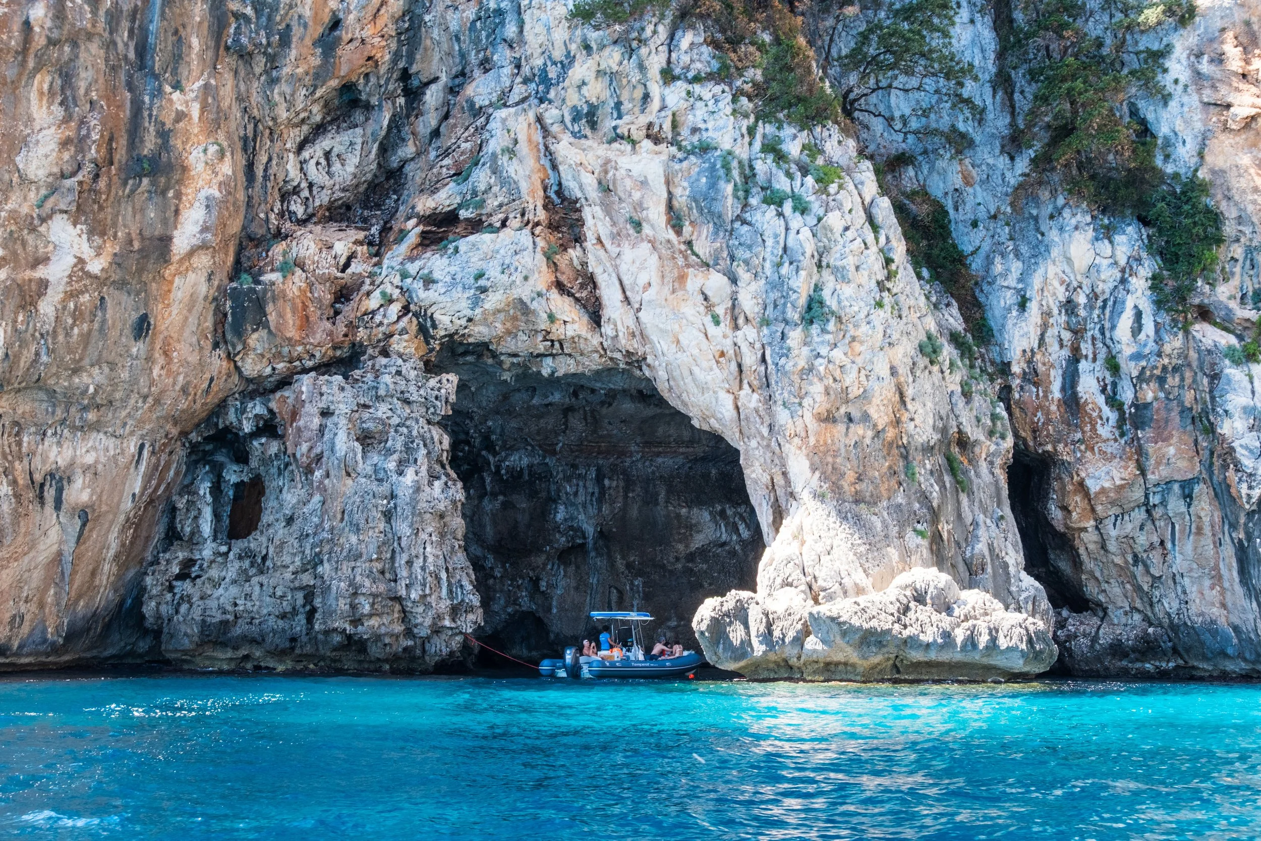 Sea cave opening in white limestone cliffs above clear water, Gulf of Orosei, Sardinia, by Zyan Sachs for Gonone Rental