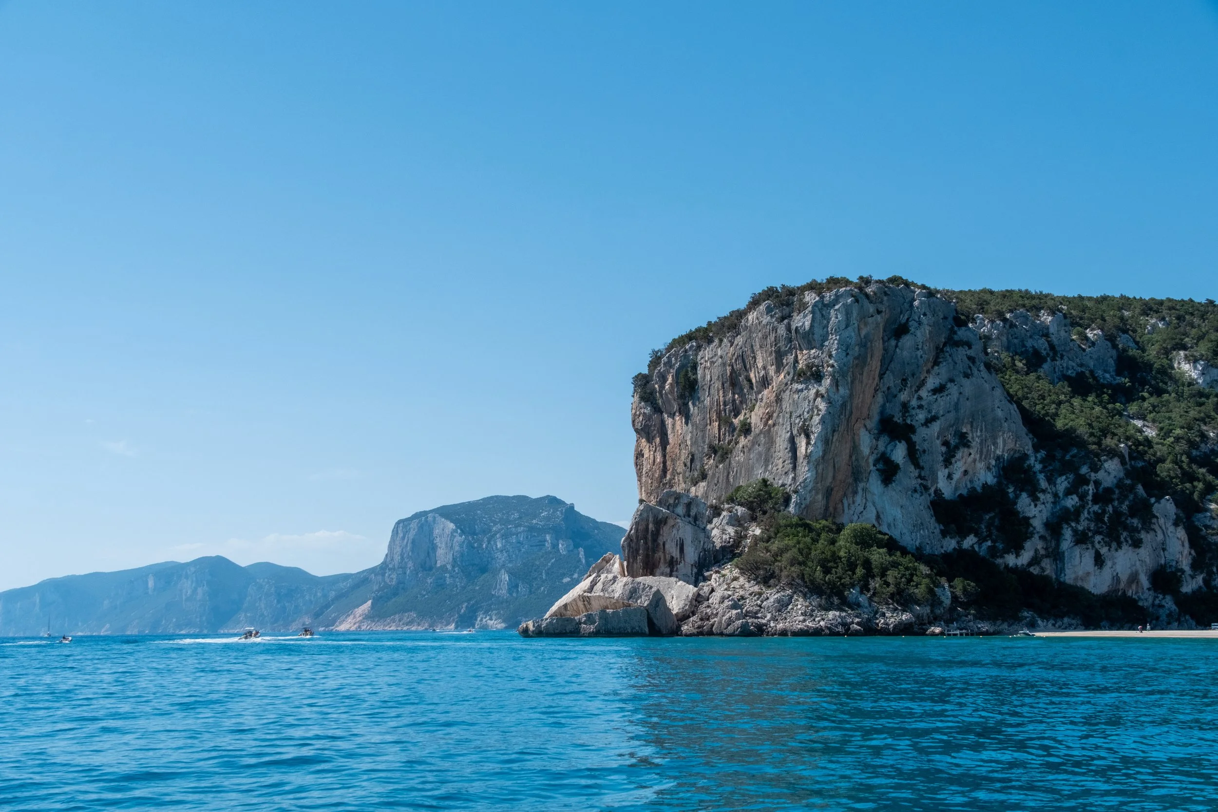 Limestone headland over deep blue water on the coast near Cala Gonone, Sardinia, by Zyan Sachs for Gonone Rental