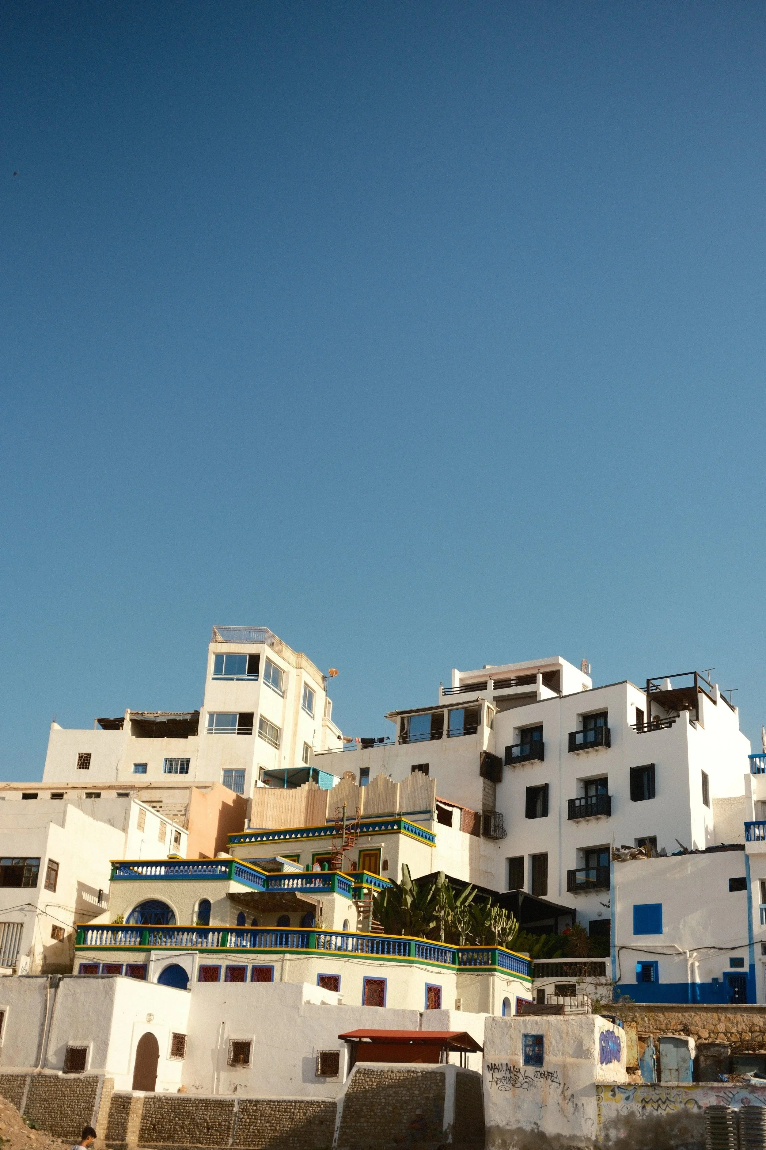 Whitewashed houses stepping up the hill under a deep blue sky, Taghazout, Morocco - fine art print by Zyan Sachs