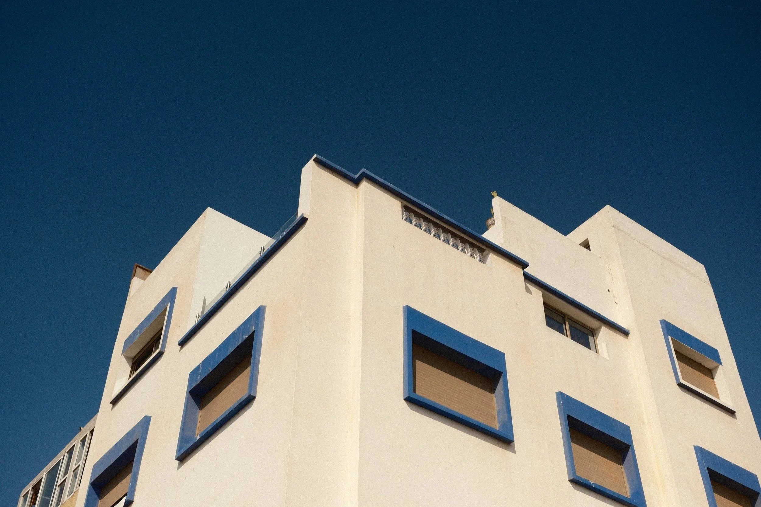 White building with blue window frames against a deep blue sky, Taghazout, Morocco - fine art print by Zyan Sachs