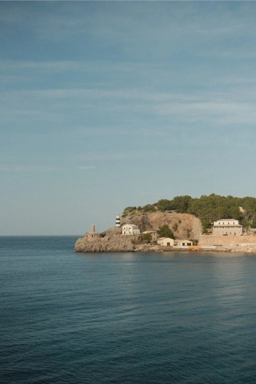 Coastal village and lighthouse point across a still blue bay, Mallorca, Spain - fine art print by Zyan Sachs