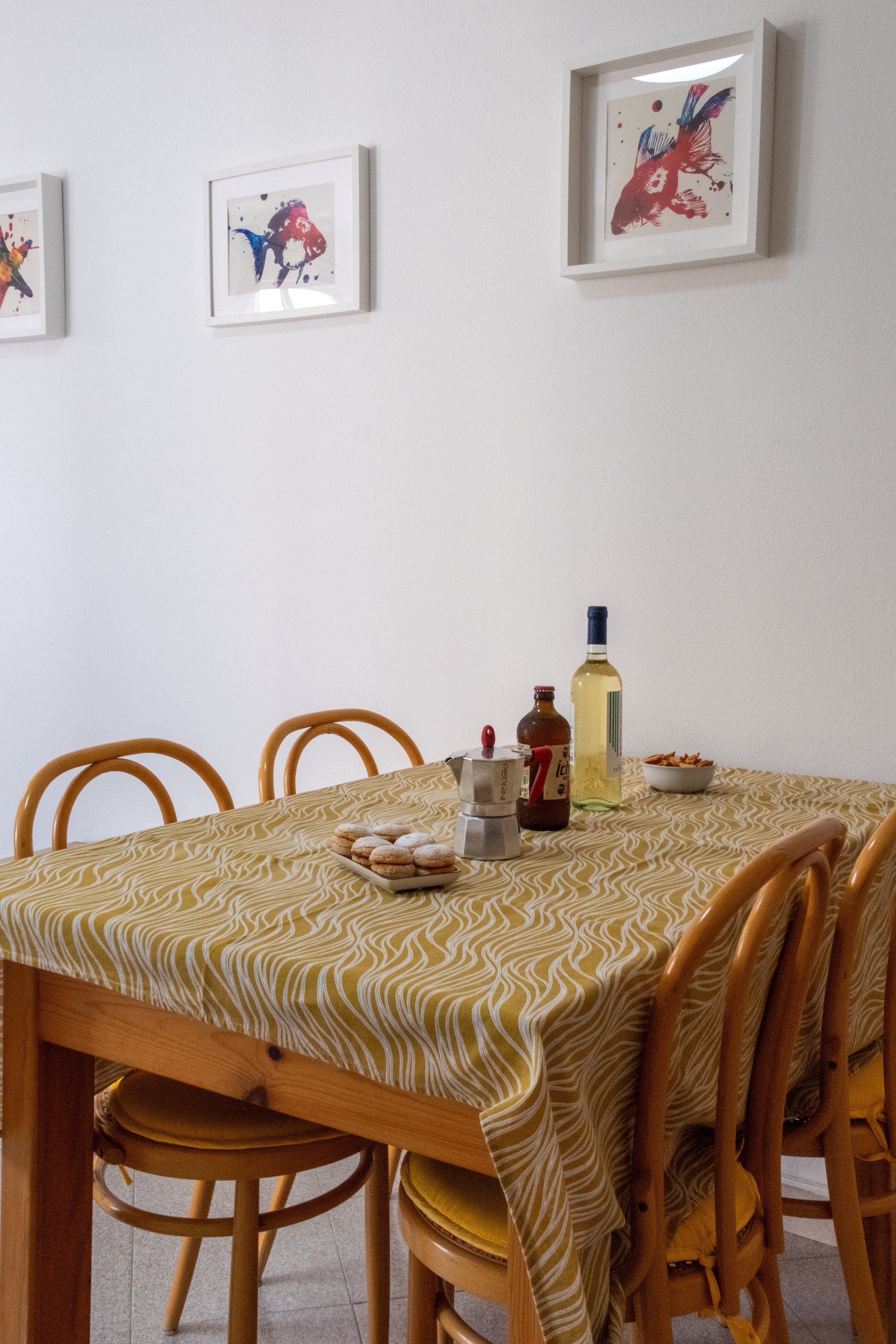 Dining table set with wine and bread under framed art at Casa Stefano, Sardinia, by Zyan Sachs