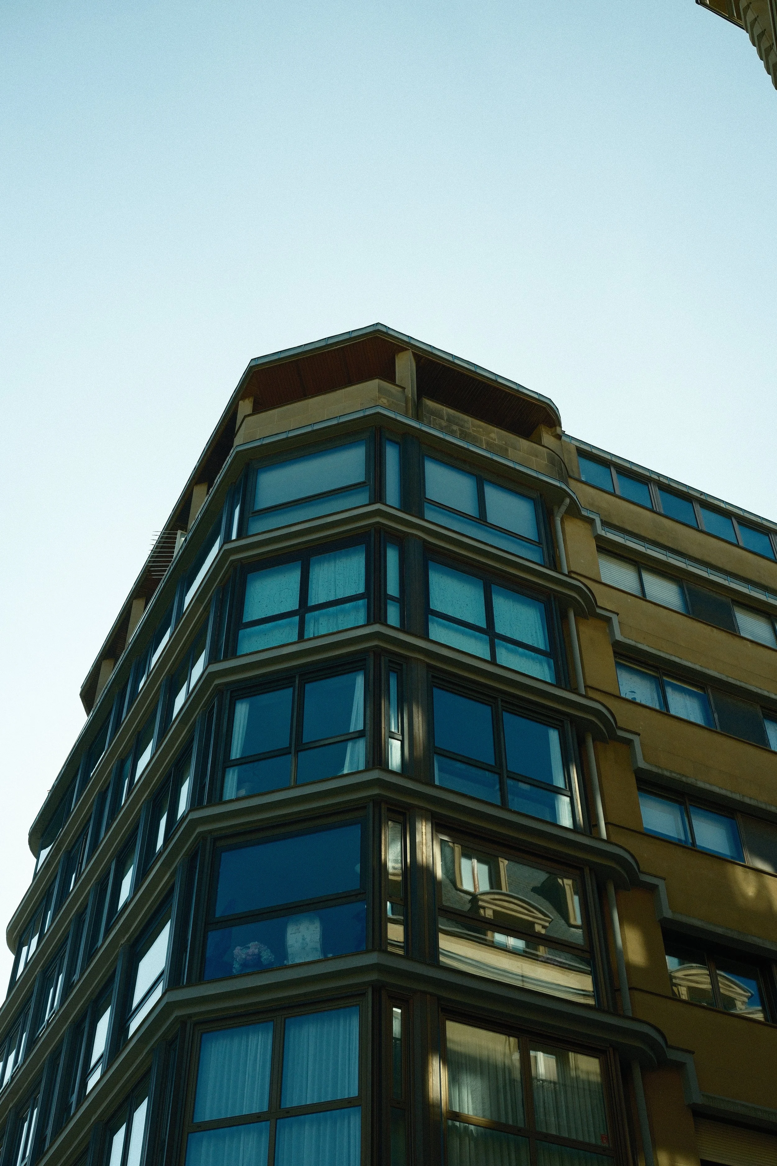 Curved modern apartment building with bay windows against a blue sky, Basque Country, Spain, by Zyan Sachs