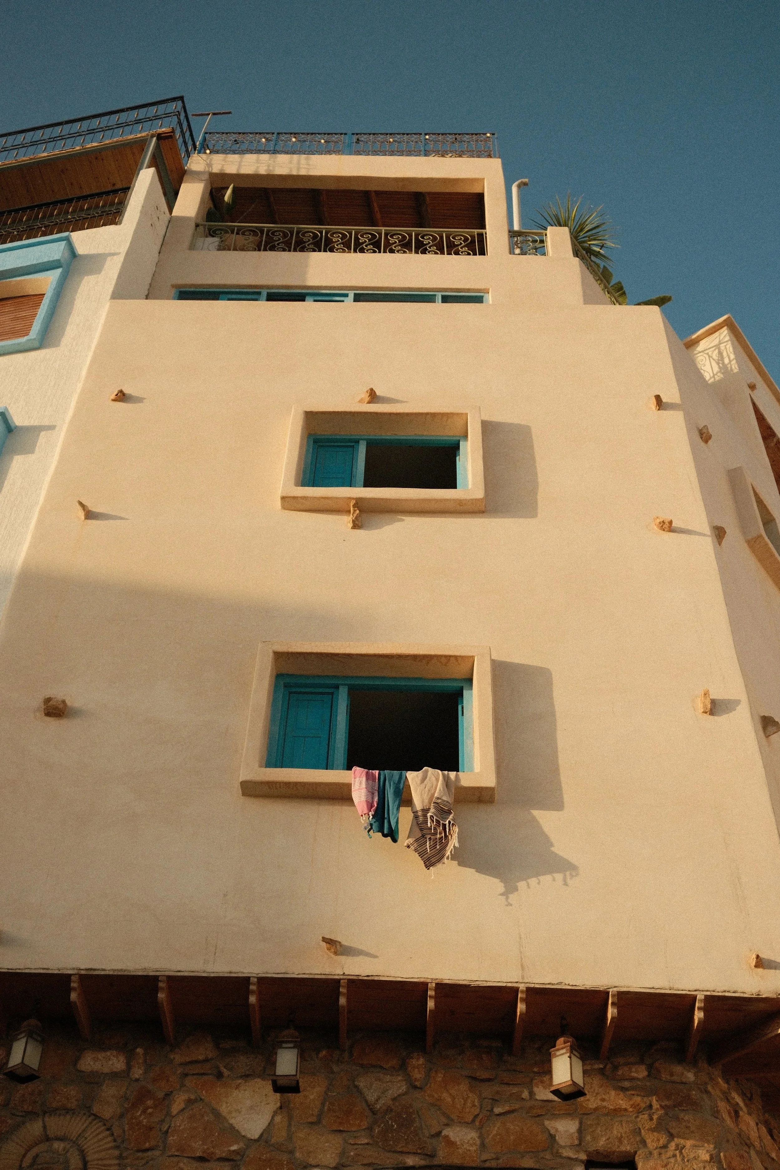 Sunlit cream building with blue shutters, Taghazout, Morocco - fine art print by Zyan Sachs