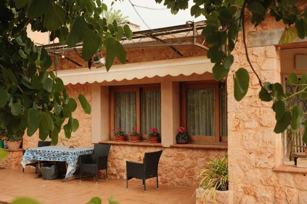 Shaded stone terrace with a table and armchairs framed by vines, Mallorca, Spain - fine art print by Zyan Sachs
