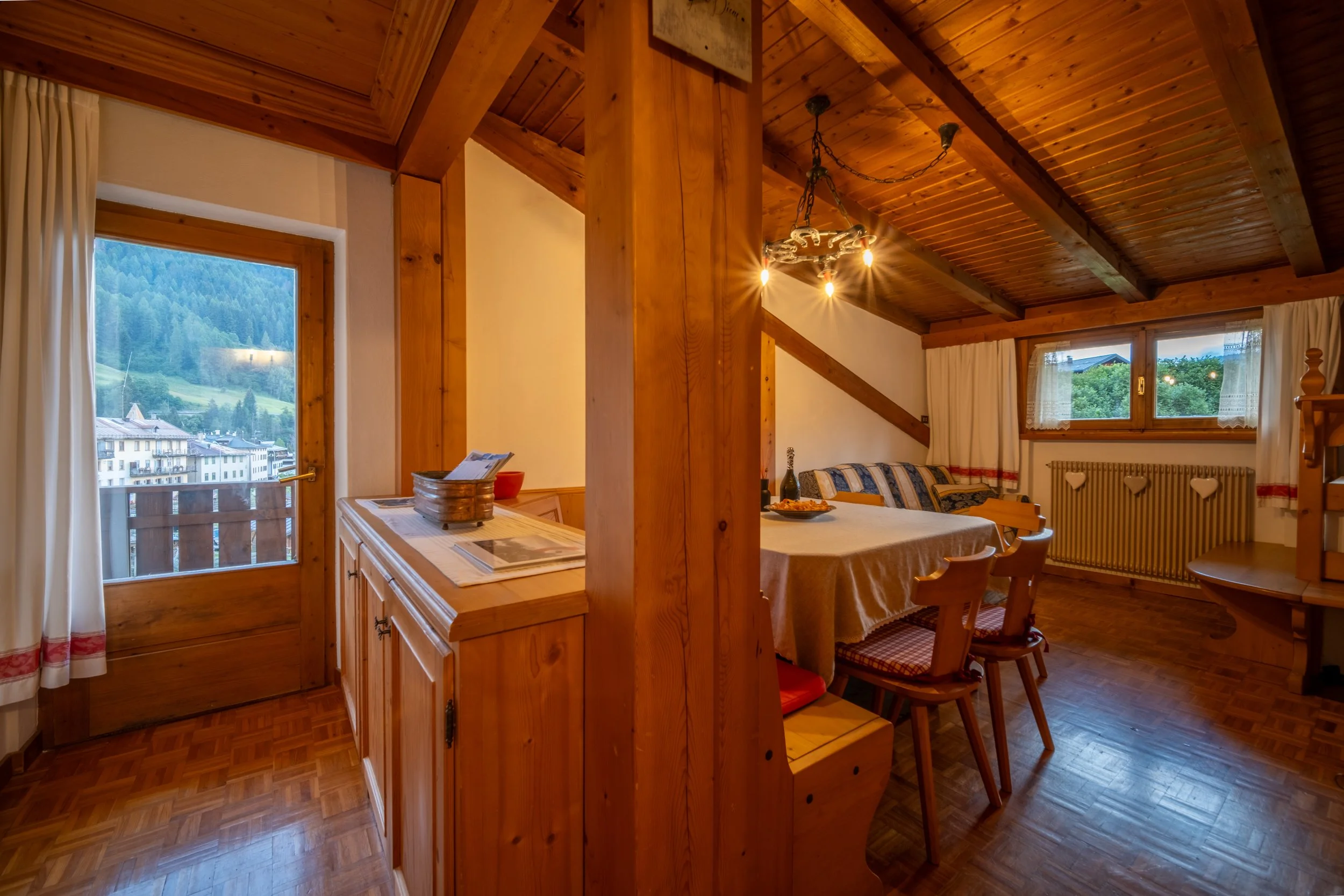 Wood-paneled living area with kitchen and dining table at Al Borgo da Agata, Dolomites, by Zyan Sachs