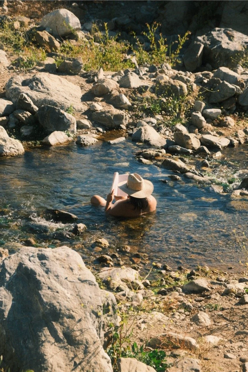 Person reading in a clear creek between granite boulders, Big Sur, California - fine art print by Zyan Sachs