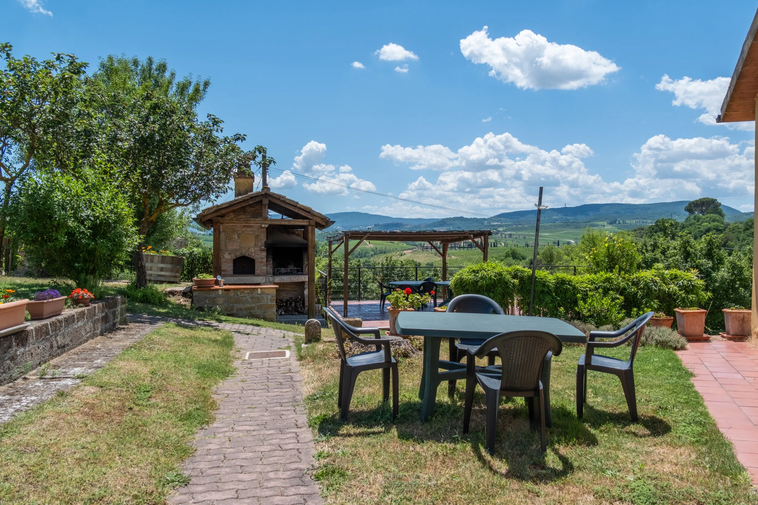 Garden dining table beside the stone oven on the lawn at Agriturismo Metina, Montepulciano, Tuscany, by Zyan Sachs