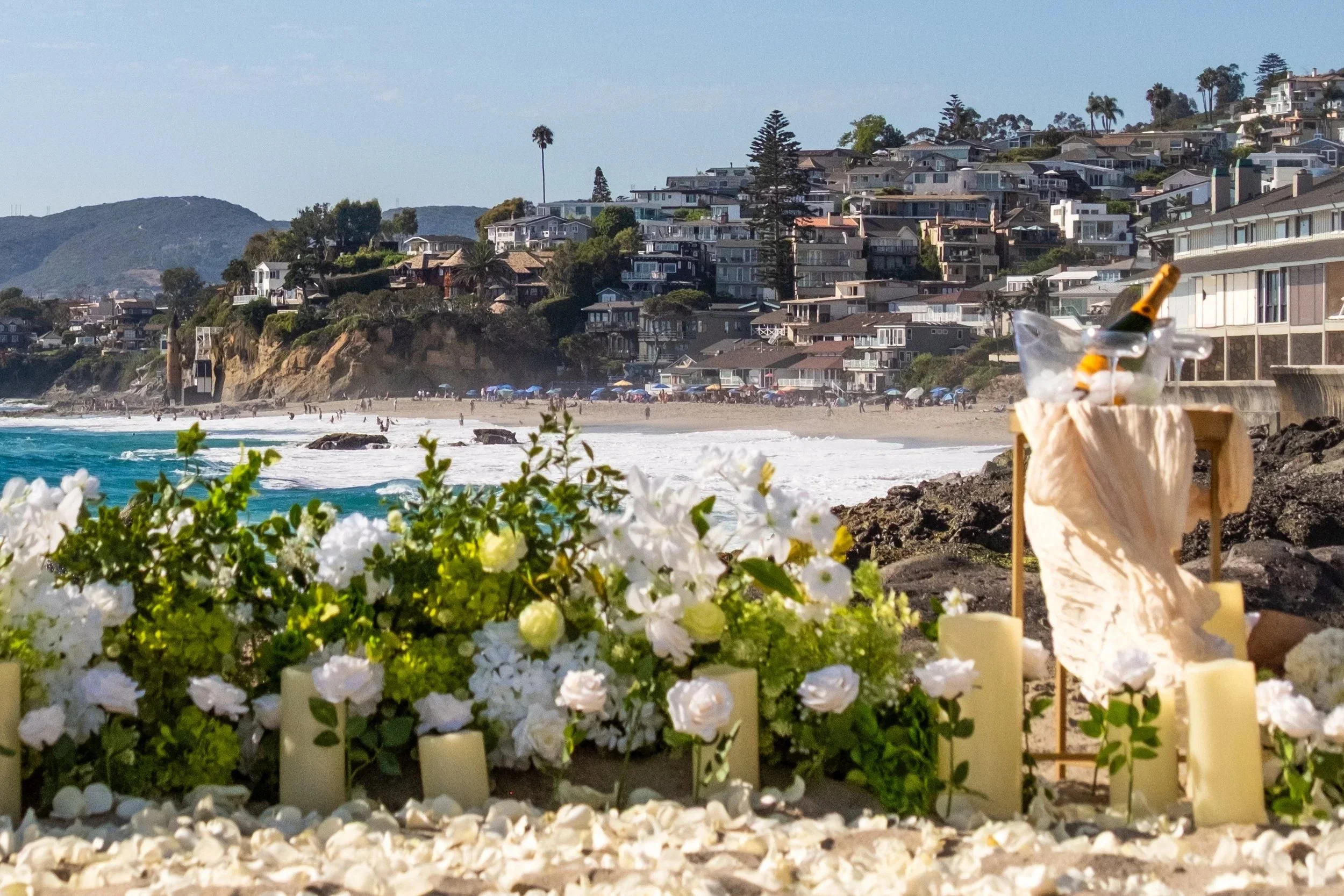 Beachside proposal setup with white flowers, candles and champagne above the cove, Southern California - proposal photography by Zyan Sachs