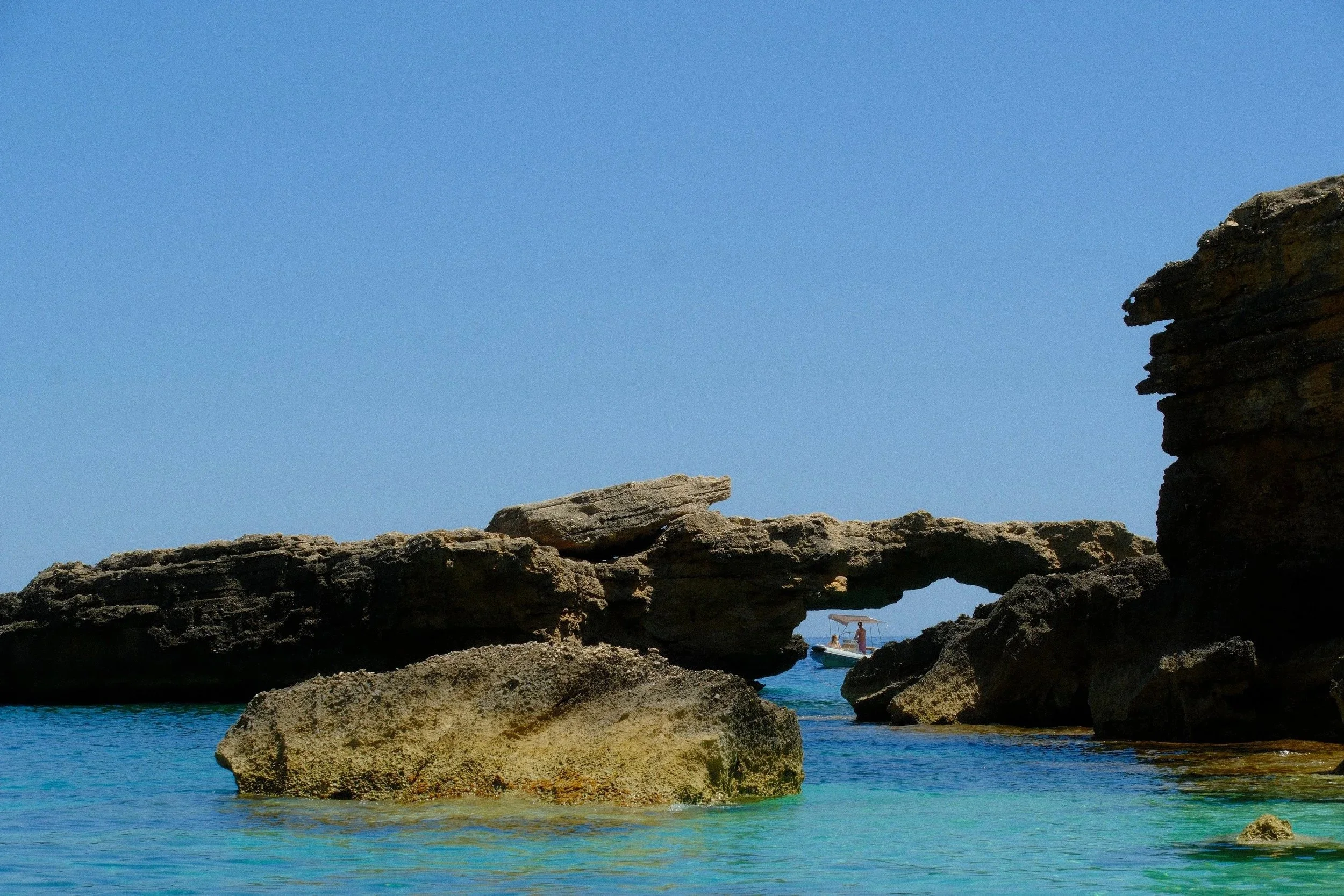 Natural rock arch rising from a calm turquoise sea, Gulf of Orosei, Sardinia, Italy - fine art print by Zyan Sachs