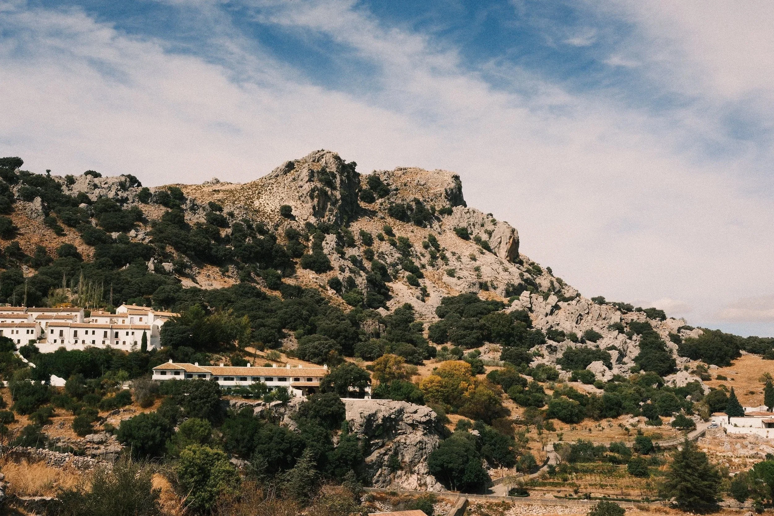 Whitewashed hilltop village below a rocky crag and castle in the Andalusian countryside, Spain - fine art print by Zyan Sachs