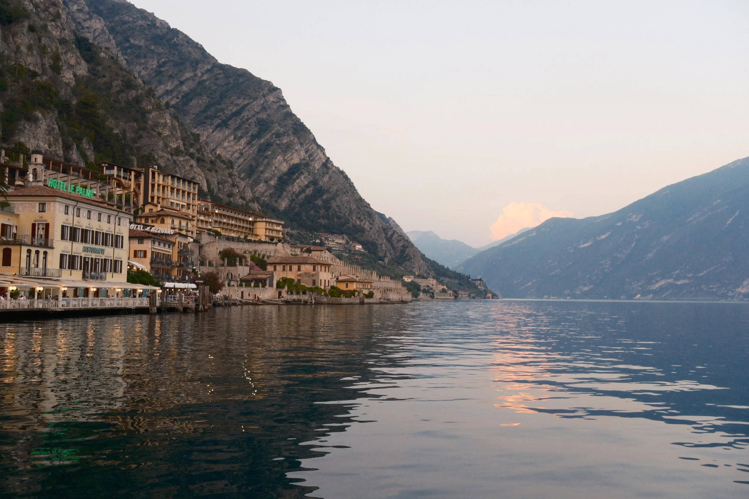 Limone sul Garda waterfront and cliffs reflected in calm water at dusk, Lake Garda, Italy, by Zyan Sachs
