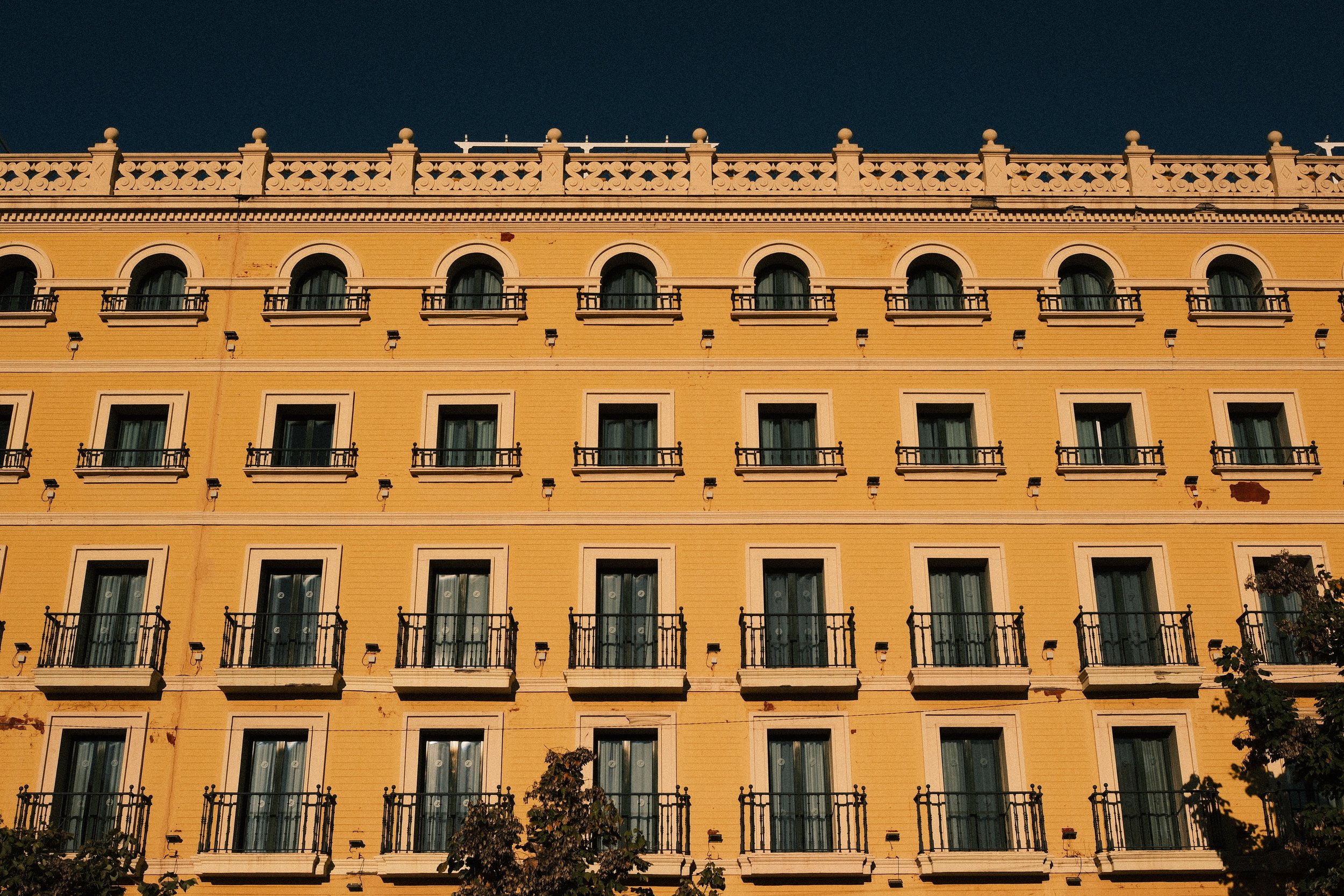Golden façade with rows of balconies against a deep blue sky, Granada, Andalucía, Spain, by Zyan Sachs
