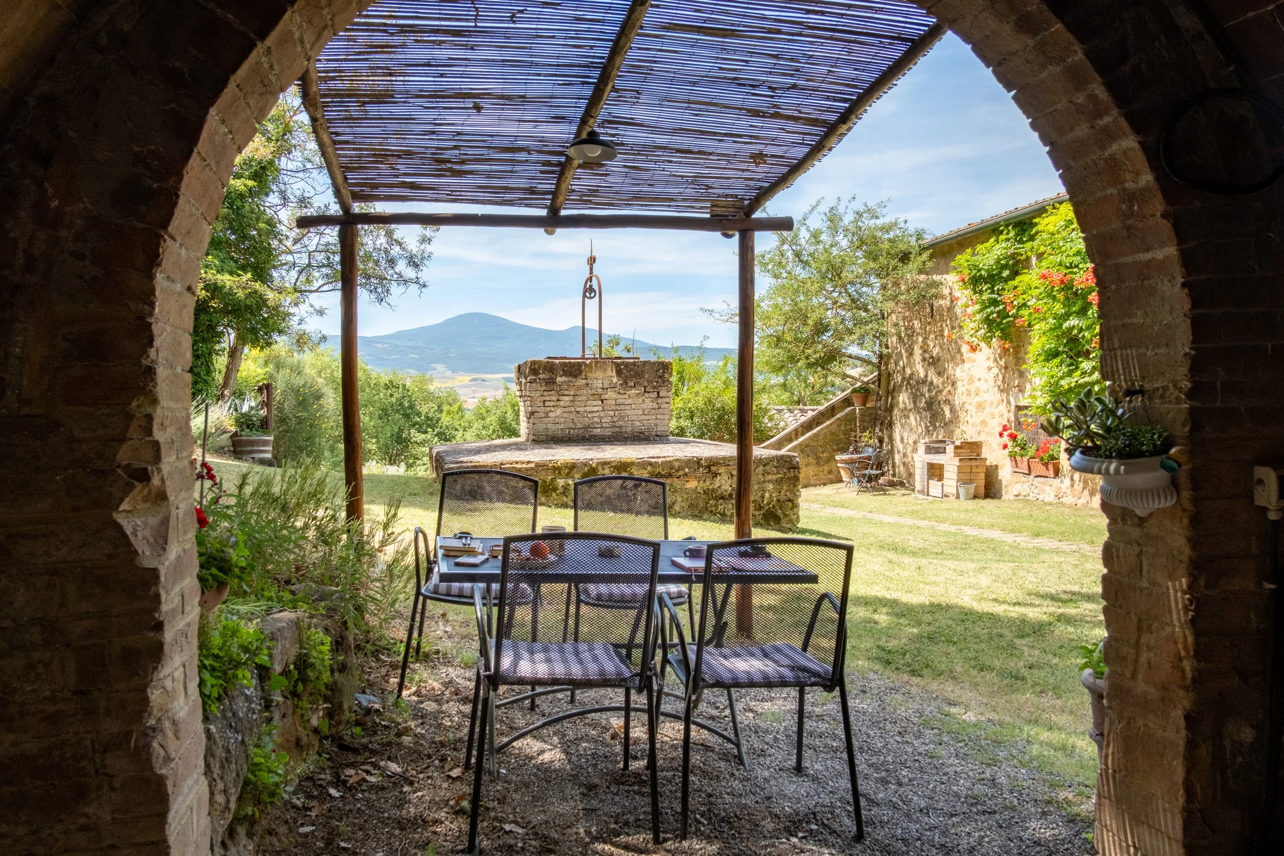 Breakfast table under a pergola seen through a stone arch at Agriturismo Selvoli, Val d'Orcia, Tuscany, by Zyan Sachs