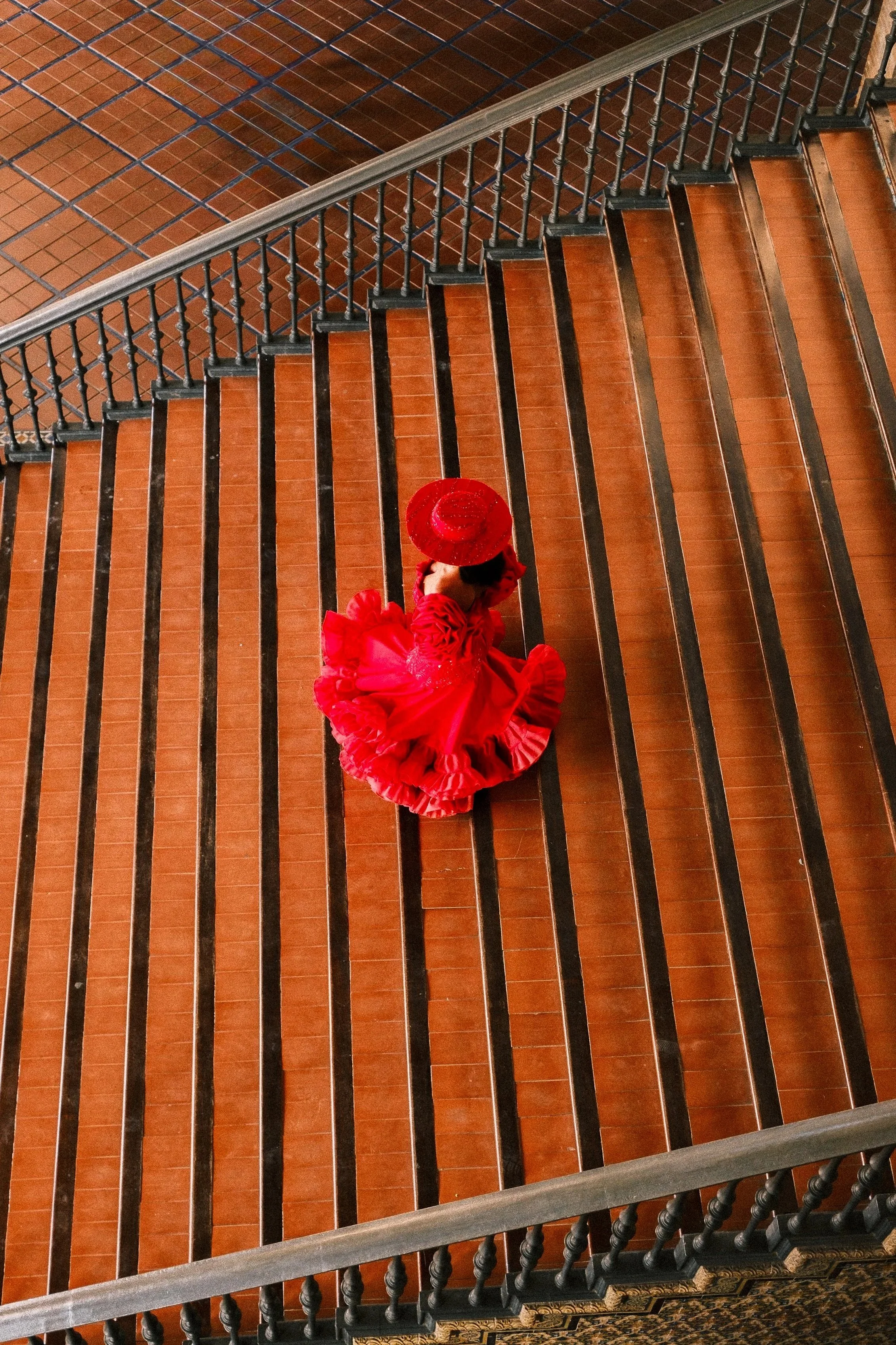 Flamenco dancer in a red dress and hat on a tiled staircase seen from above, Sevilla, Andalucía, Spain, by Zyan Sachs