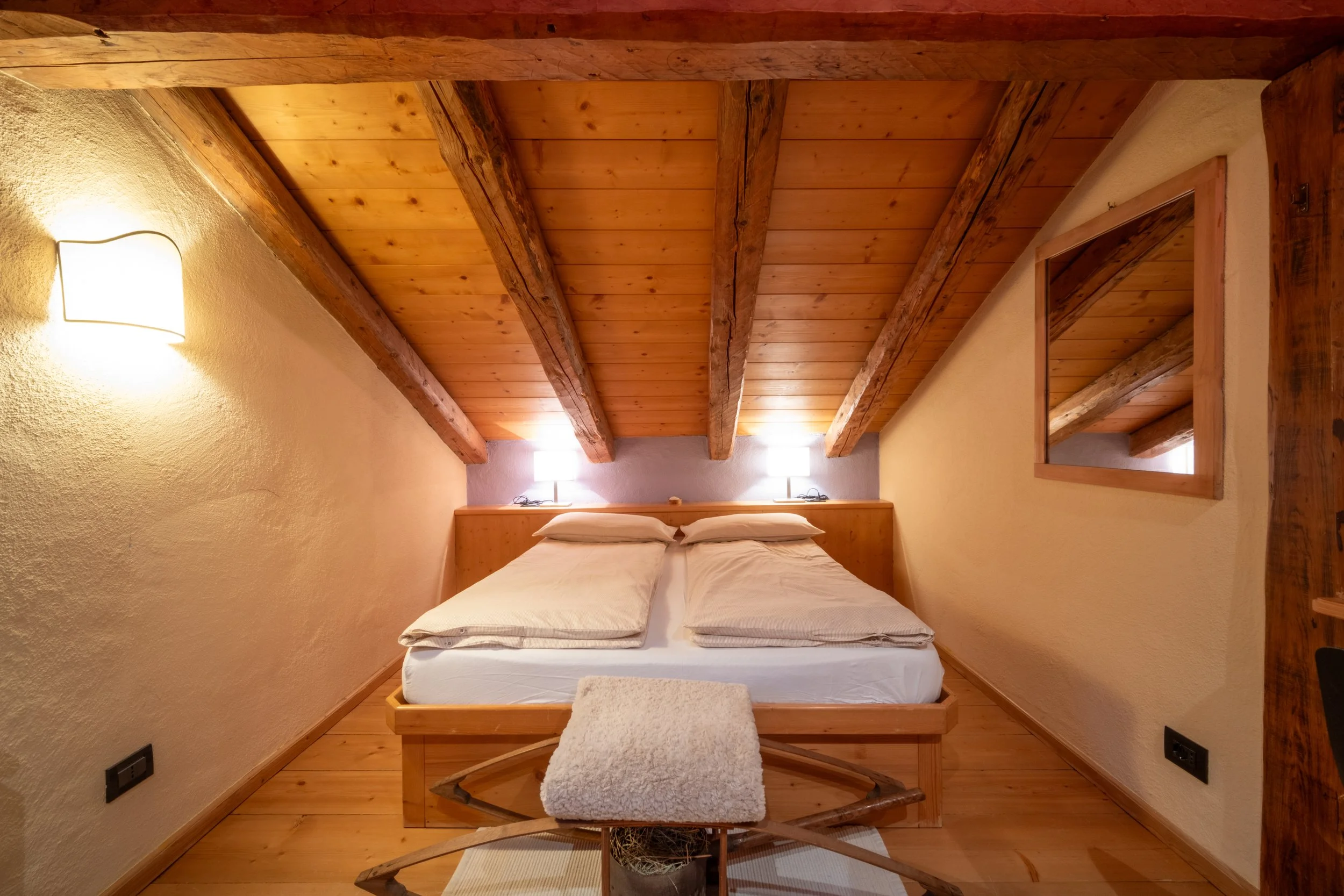 Double bedroom under a wood-beamed ceiling at Al Borgo da Agata, Dolomites, by Zyan Sachs