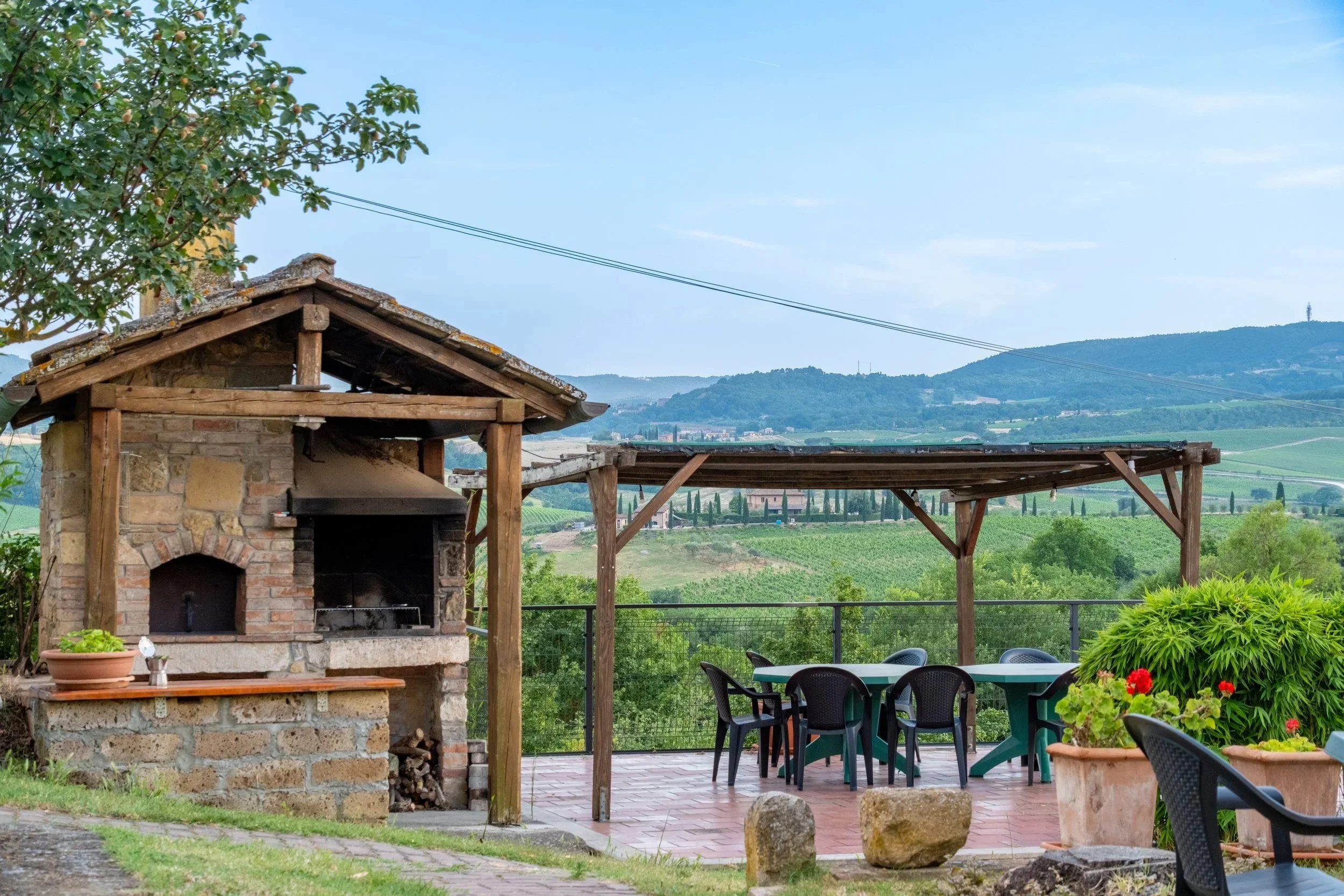 Stone wood-fired oven and pergola dining terrace with hill views at Agriturismo Metina, Montepulciano, Tuscany, by Zyan Sachs