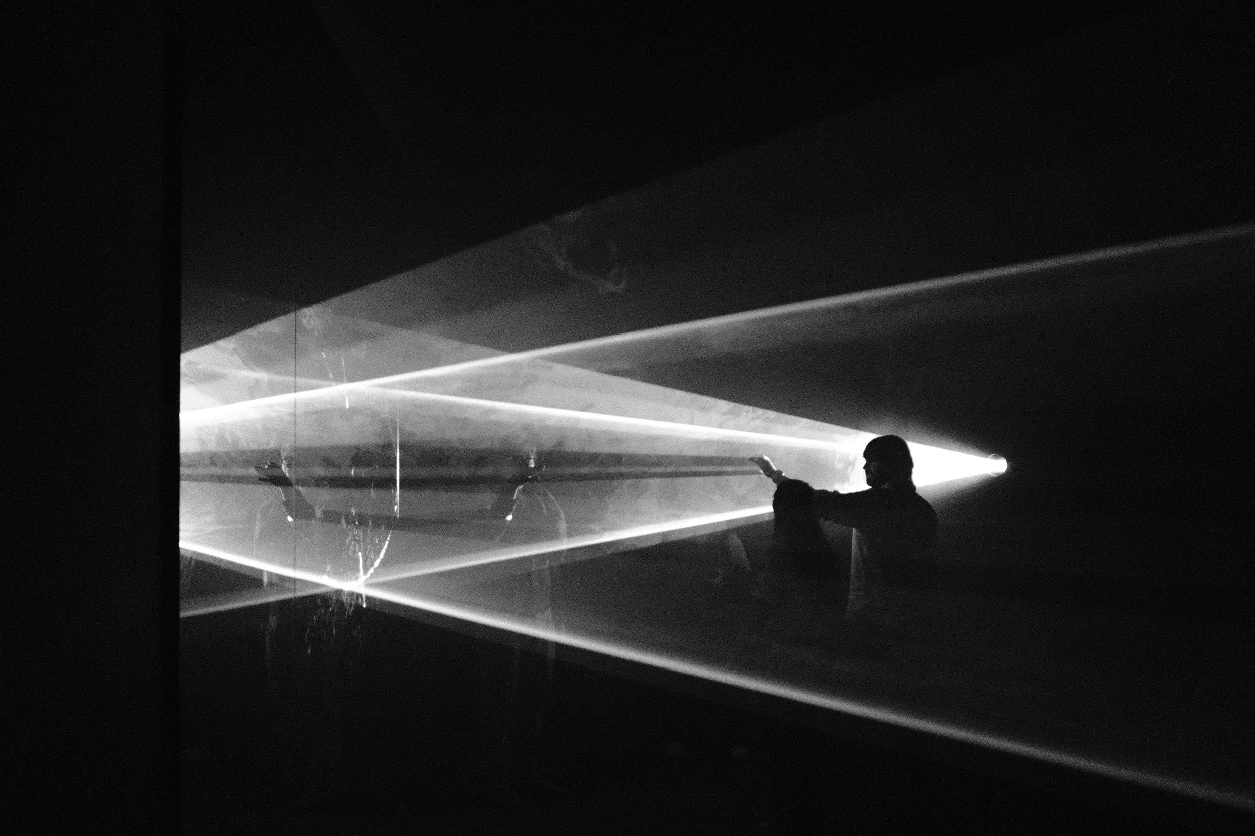 Visitor silhouetted in beams of a light installation in a dark gallery, Bilbao, Basque Country, Spain, by Zyan Sachs