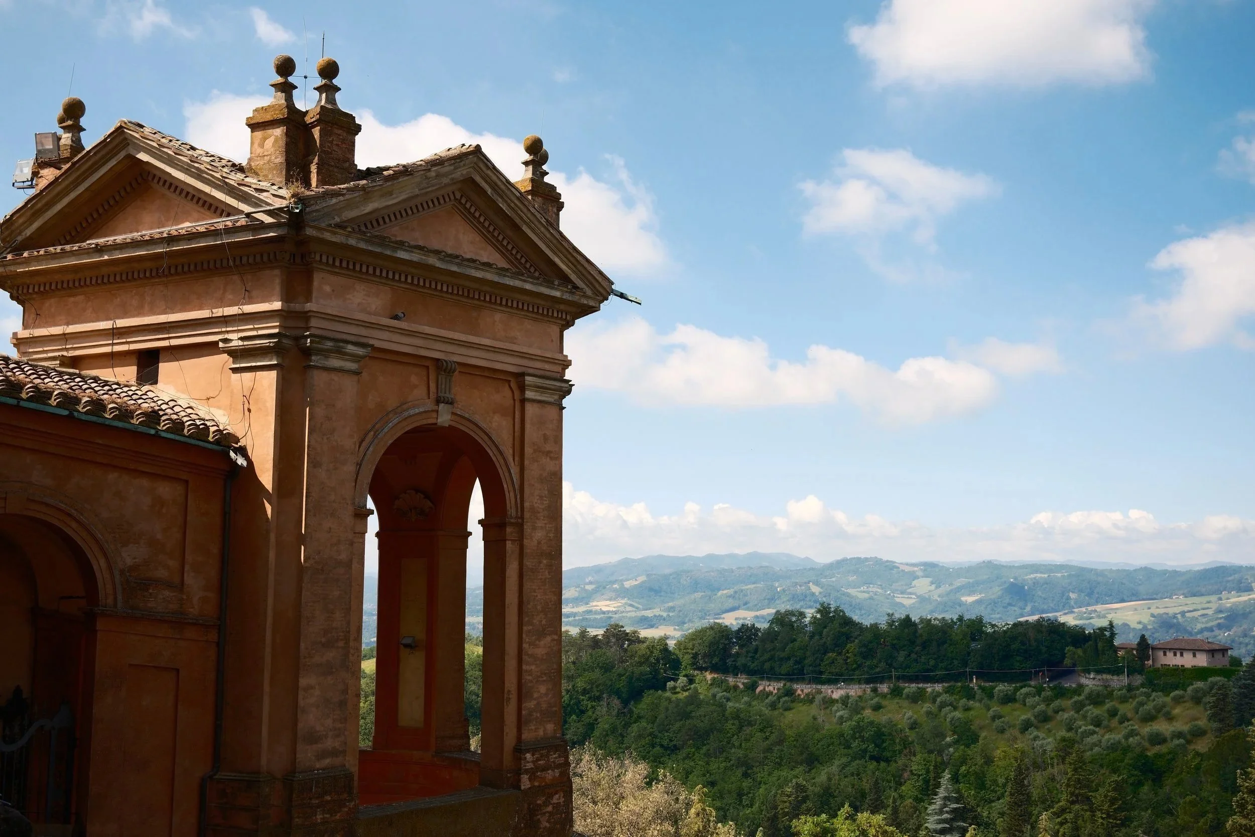 Terracotta arcade of the San Luca portico overlooking the green hills outside Bologna, Italy, by Zyan Sachs