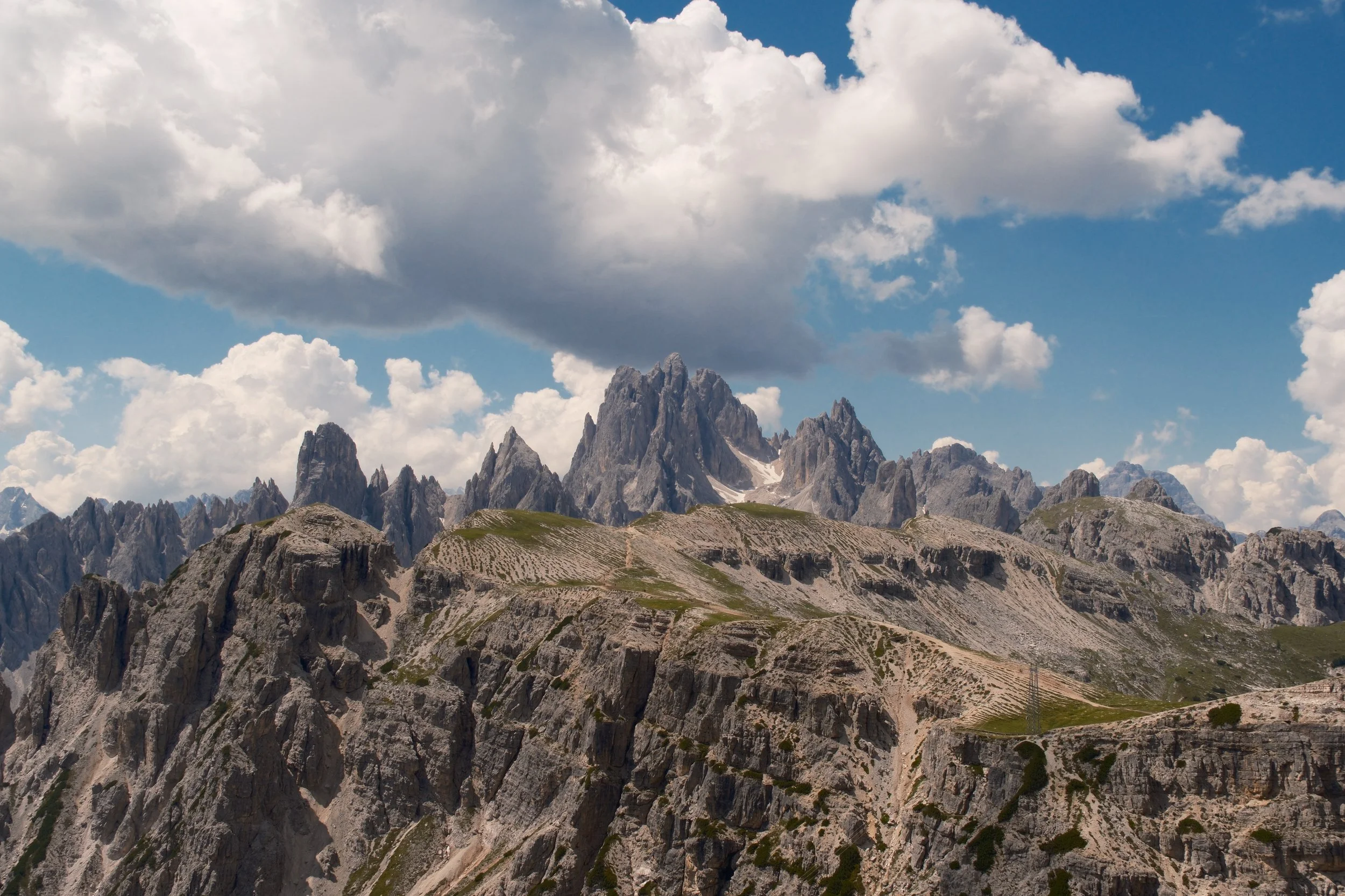Jagged Cadini di Misurina spires under towering cumulus clouds, Dolomites, Italy, by Zyan Sachs