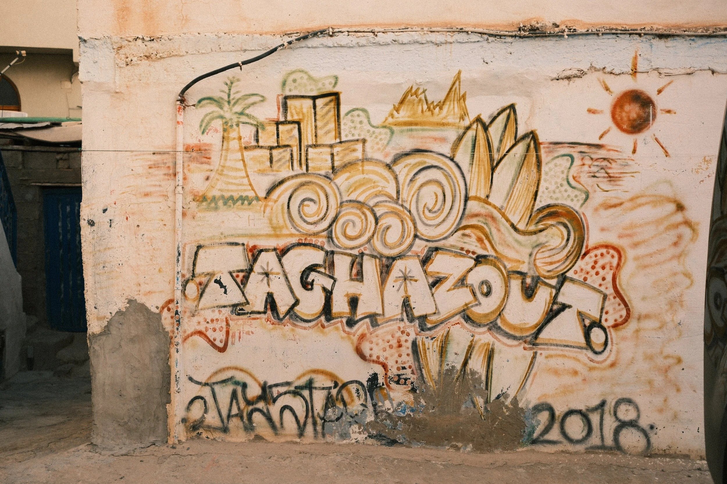 Graffiti mural reading Taghazout on a whitewashed wall, Taghazout, Morocco - fine art print by Zyan Sachs