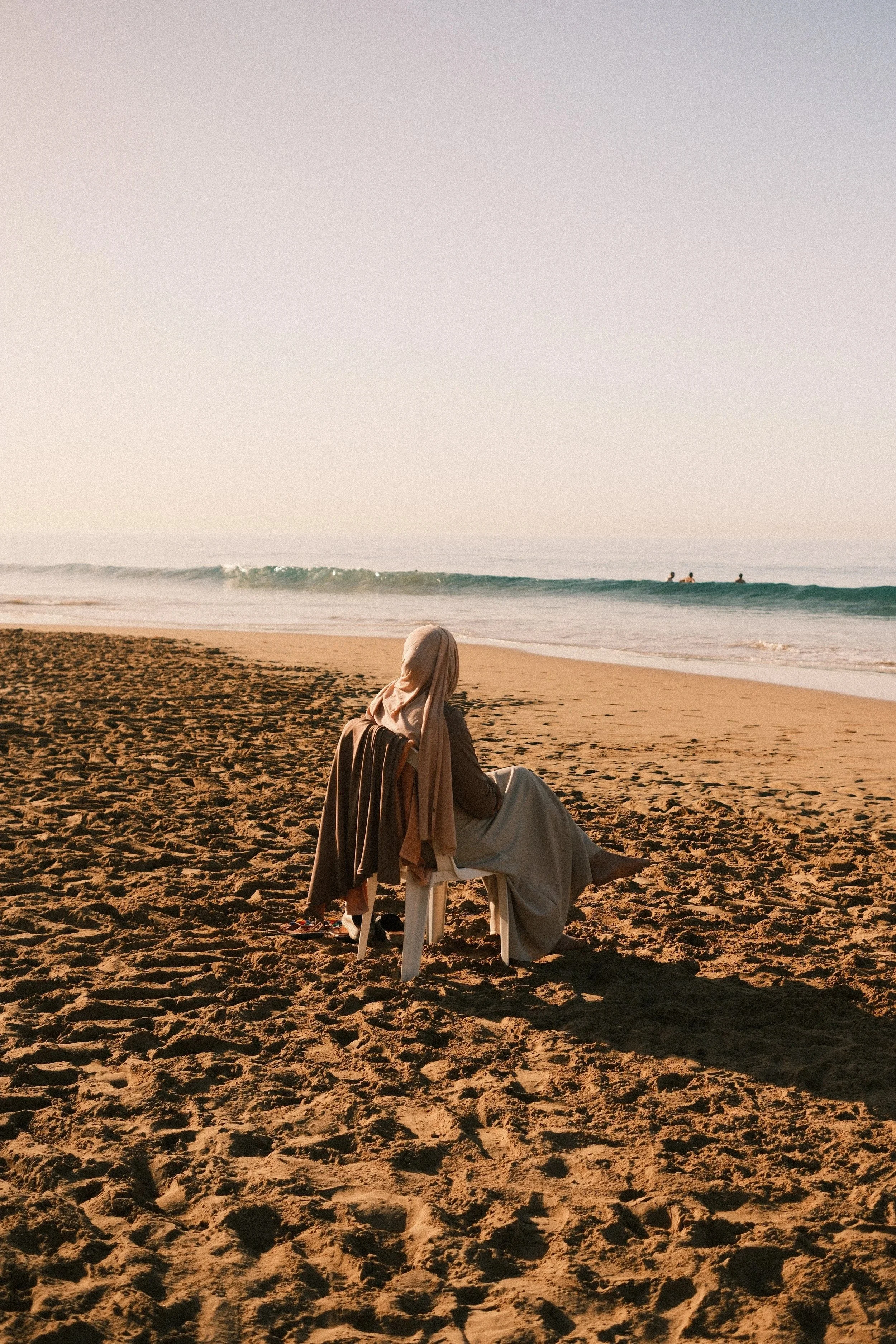 Camel kneeling on the sand by the water's edge in soft light, Taghazout, Morocco - fine art print by Zyan Sachs