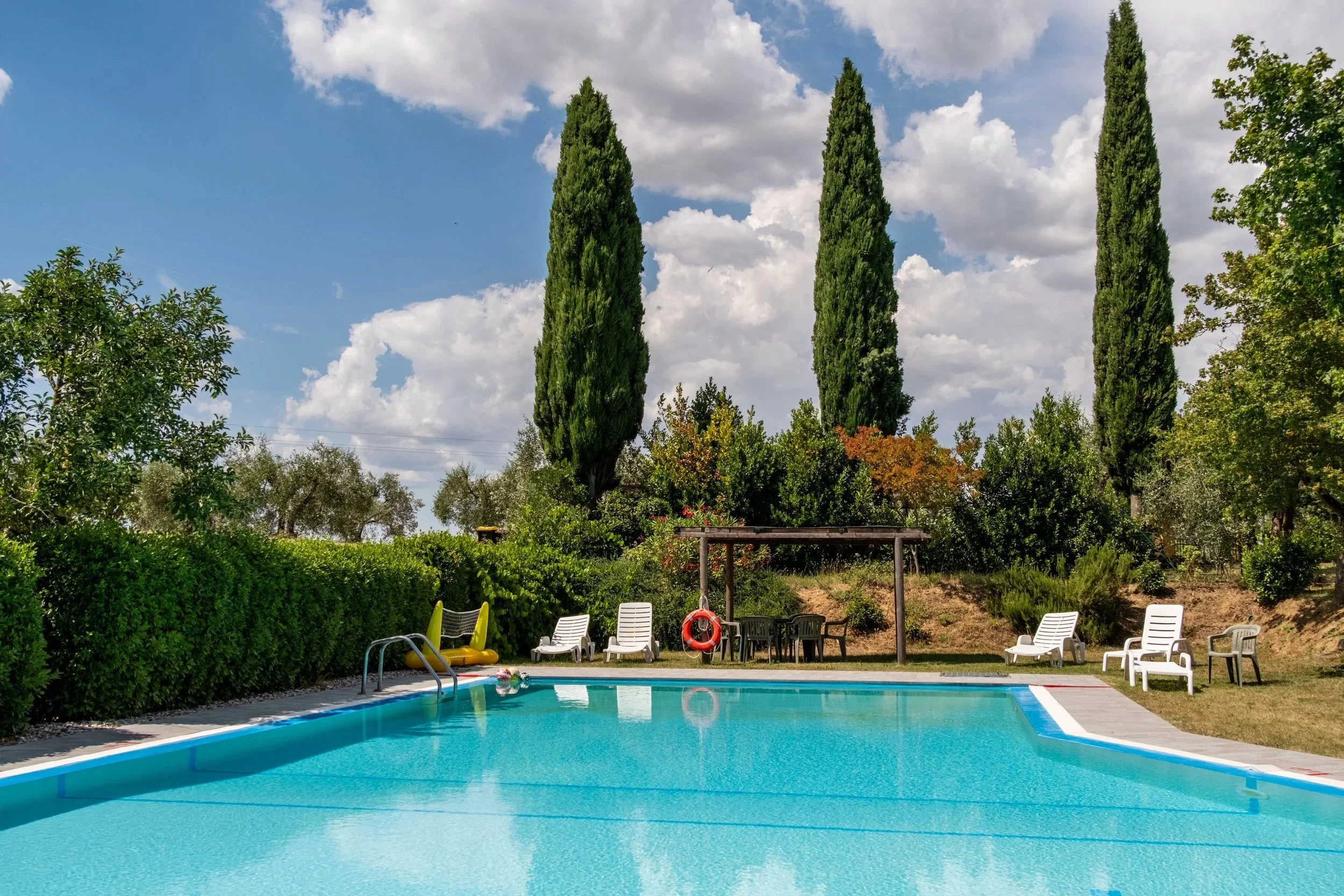 Swimming pool lined with cypress trees and sun loungers at Agriturismo Metina, Montepulciano, Tuscany, by Zyan Sachs