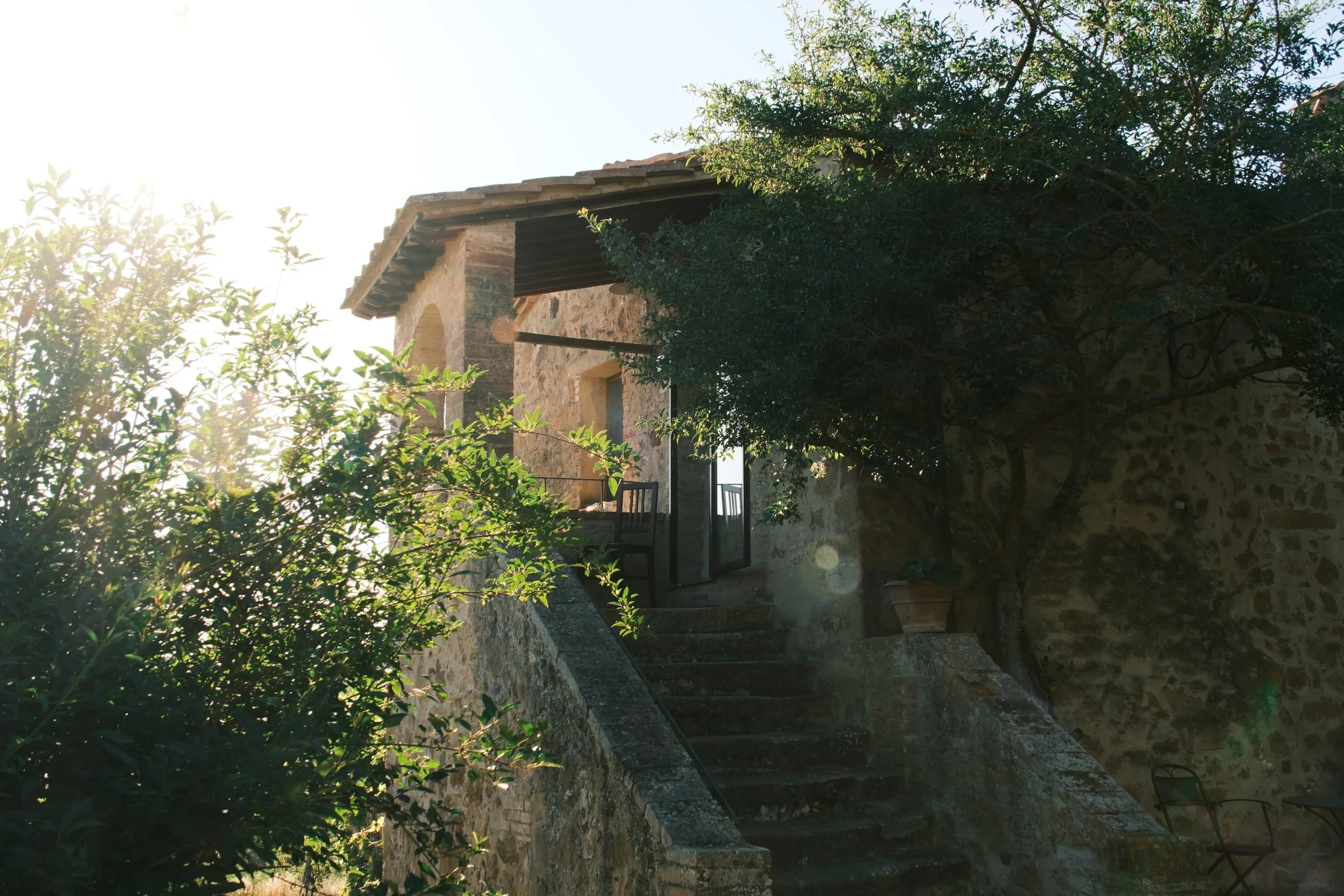 Stone staircase leading to a covered loggia of a Tuscan farmhouse in soft morning sunlight, Italy, by Zyan Sachs