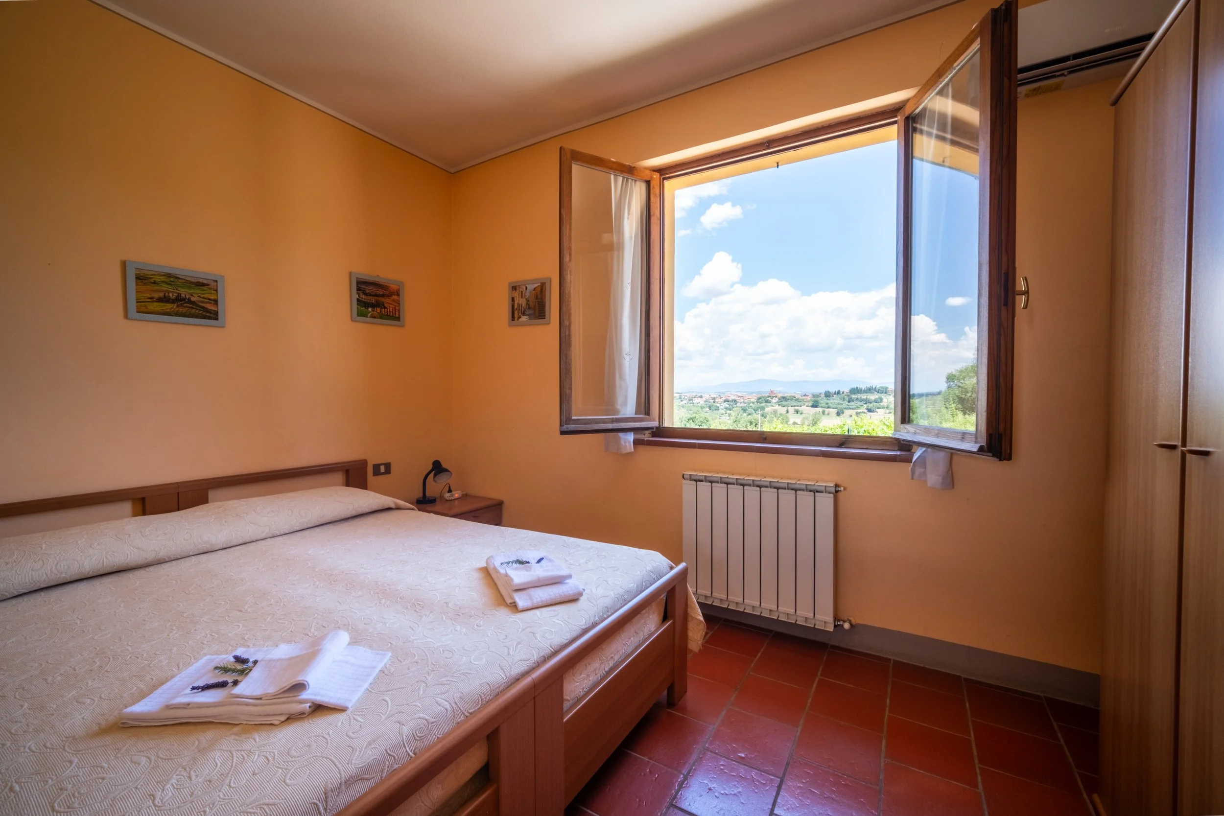 Twin bedroom with terracotta floors and a window over the hills at Agriturismo Metina, Montepulciano, Tuscany, by Zyan Sachs