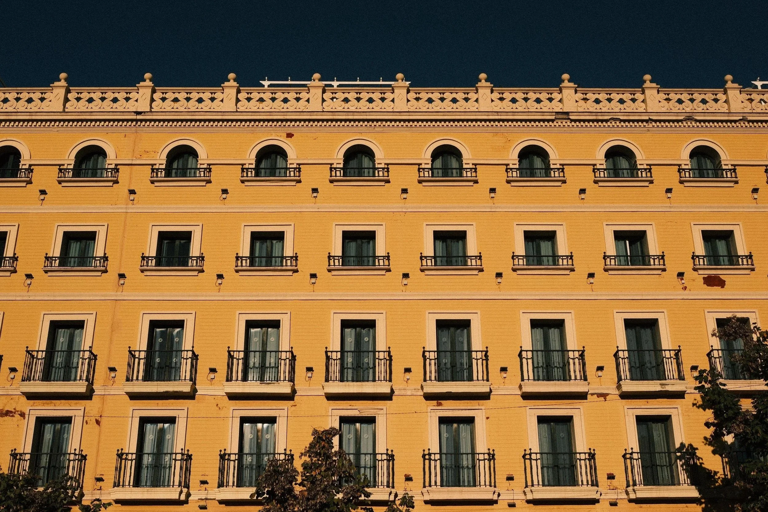 Golden façade with rows of balconies against a deep blue sky, Granada, Andalucía, Spain - fine art print by Zyan Sachs