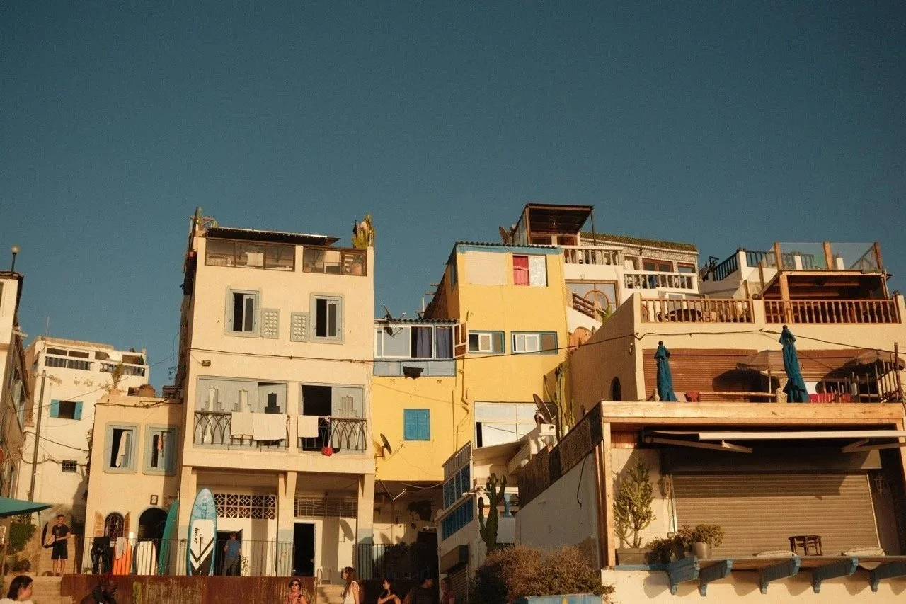 Pastel apartment buildings with balconies against a blue sky, Taghazout, Morocco - fine art print by Zyan Sachs