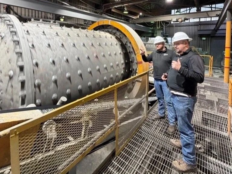 Two engineers standing by a ball mill mining process engineering