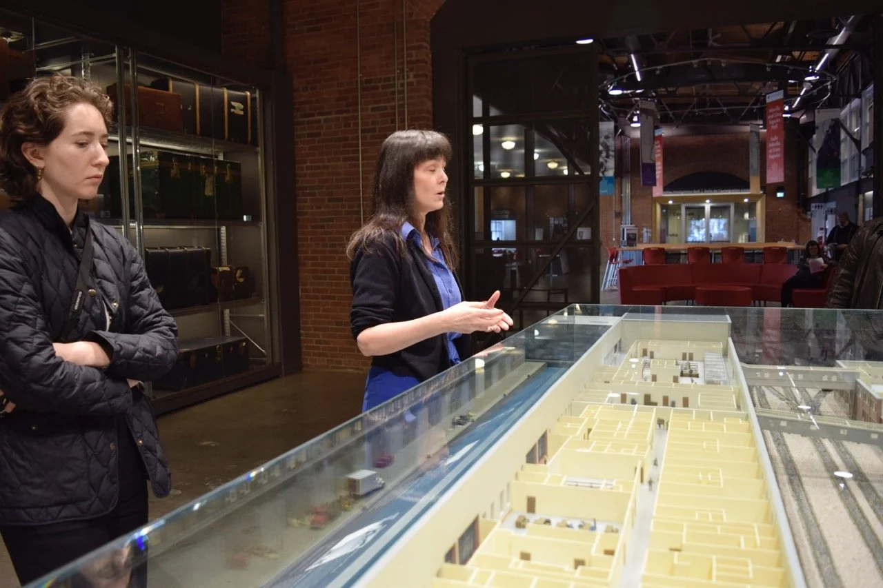 Two person standing next to miniature model of a building.