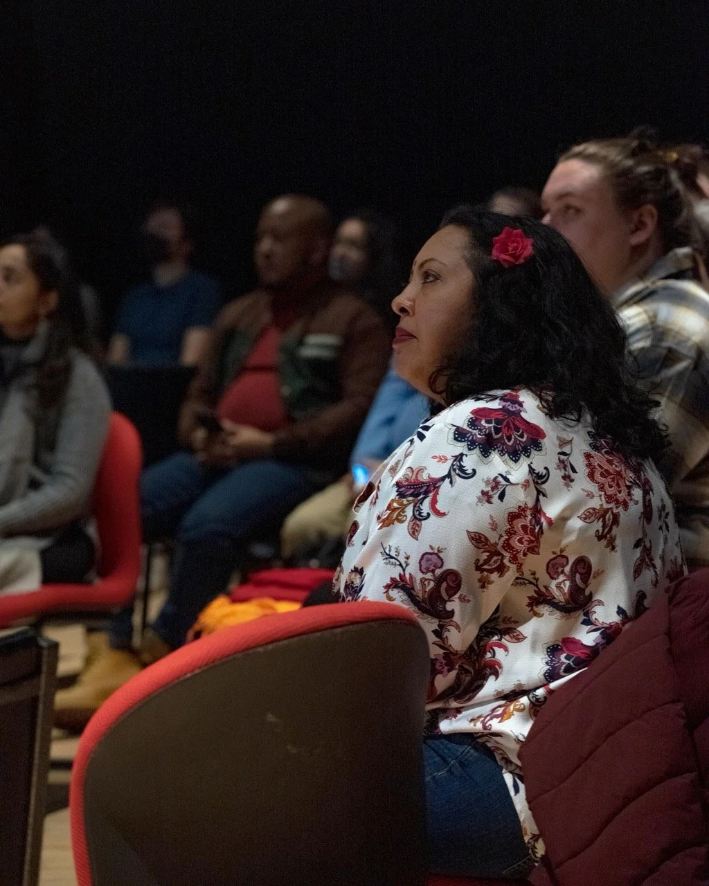 Close up of audience member watching performance from a chair.