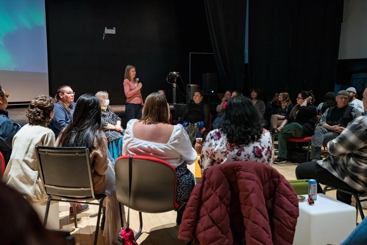 Group of people sitting in a circle watching presenter.