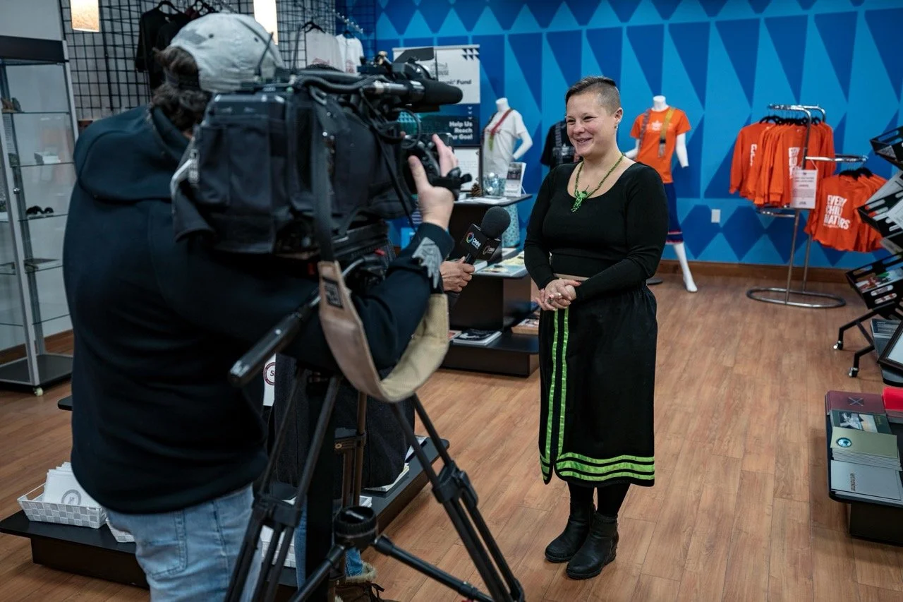 Person standing front of a news camera smiling.