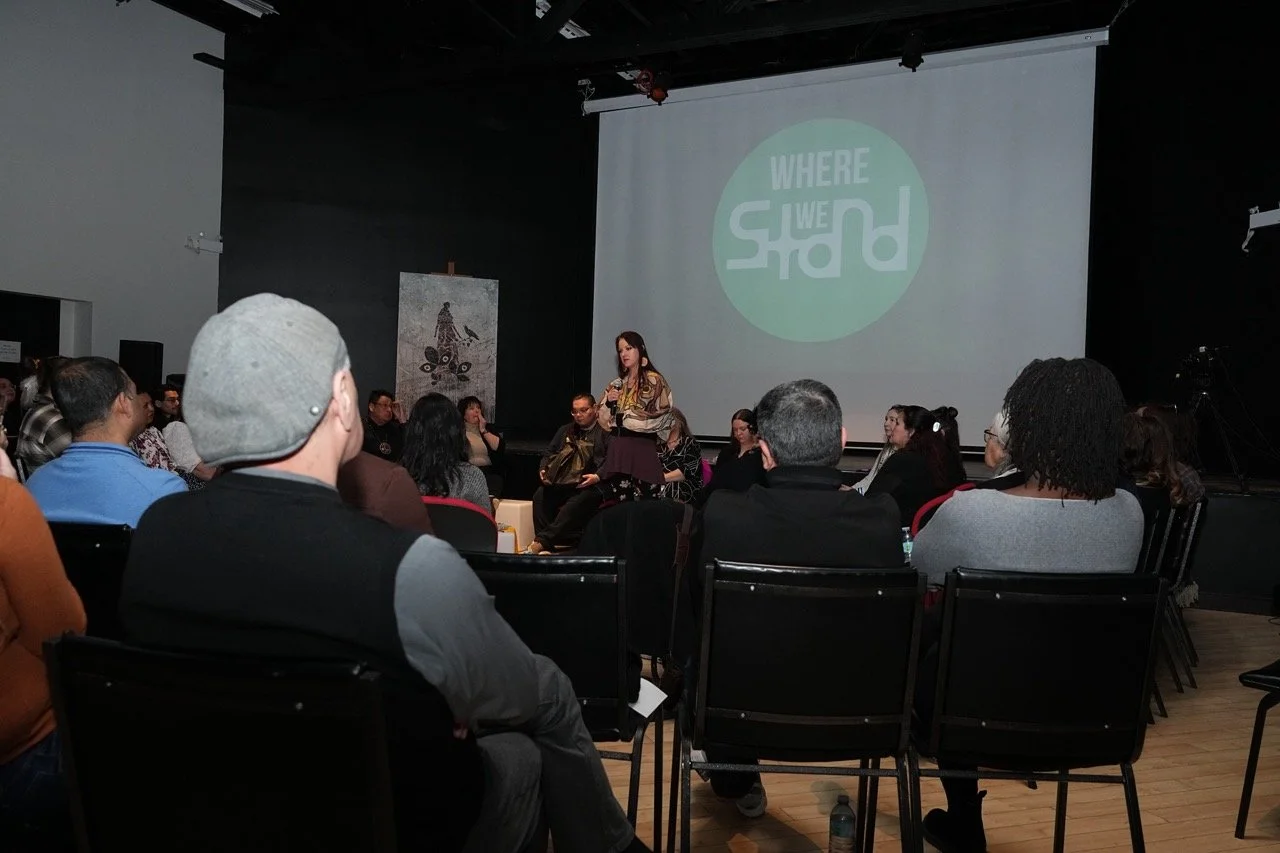 Audience watching presenter front of a "Where We Stand" logo on screen.
