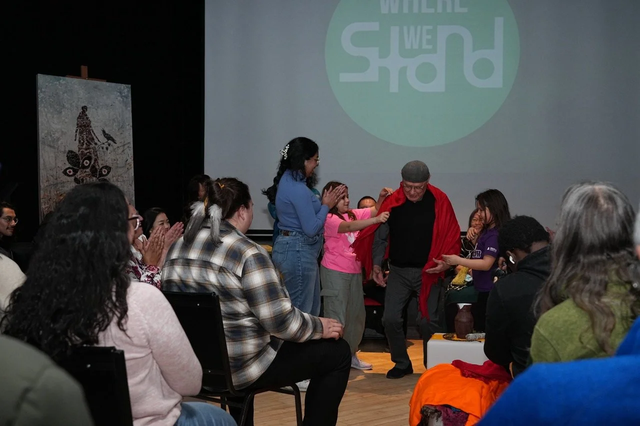 Group of people in standing in the middle of a circle front of an audience.